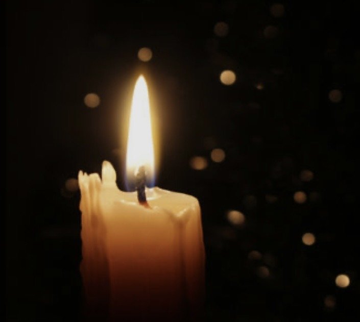 Una vela encendida en la oscuridad con chispas de luz en el fondo