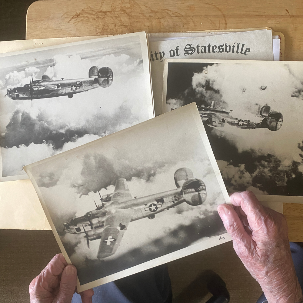 elderly hands holding World War II aircraft photographs during a living history reenactment display