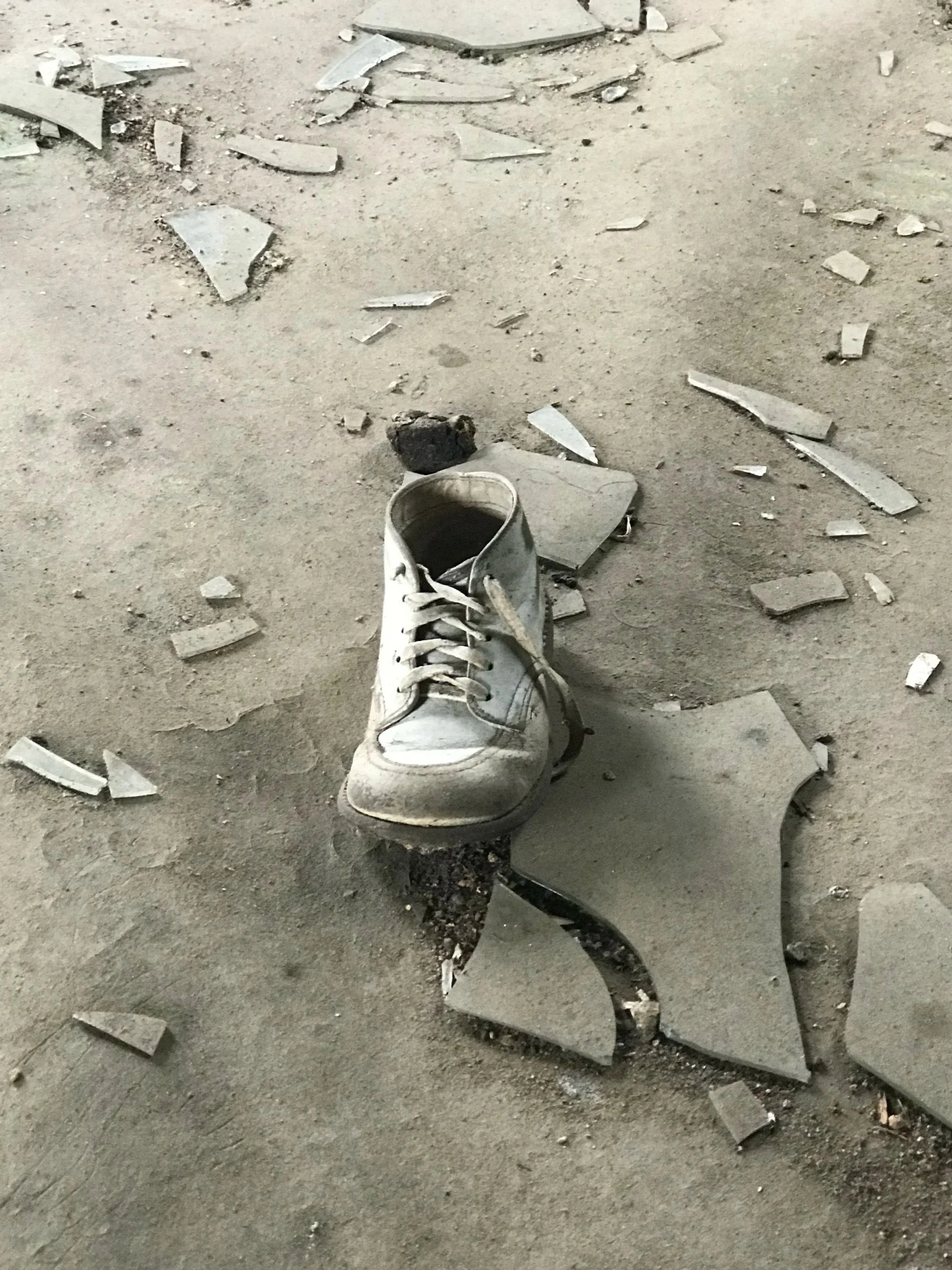 an old baby shoe on the floor of an abandoned house, surrounded by broken pieces of tile