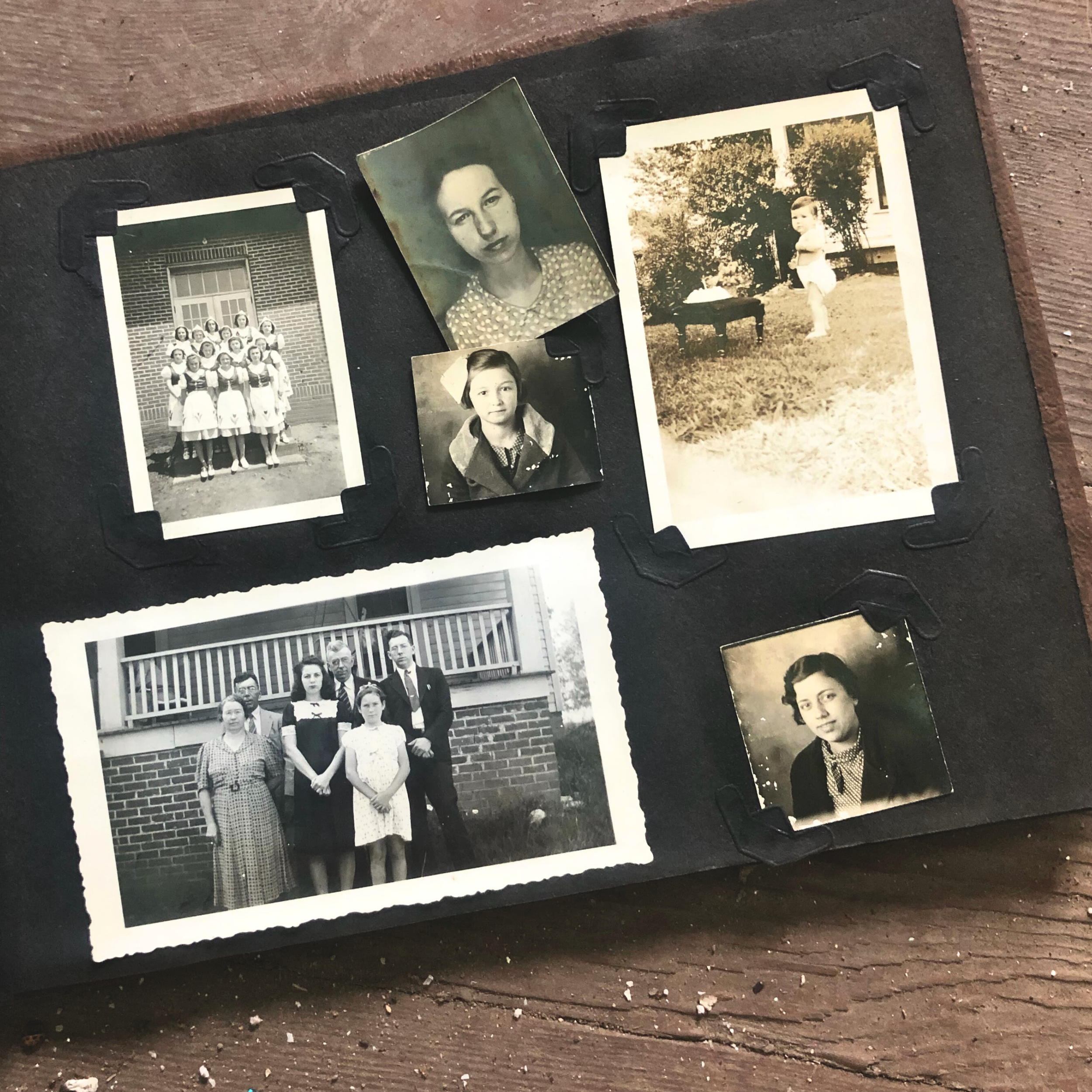 an old photo album open, showing six black and white photos of unknown people.