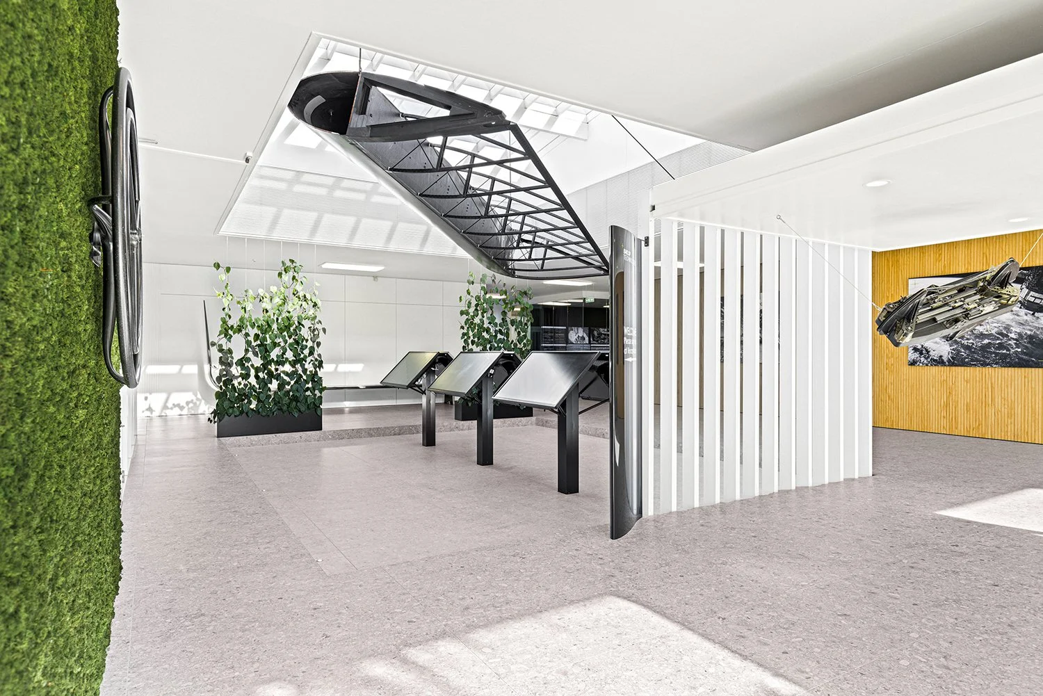 Modern museum or science center interior with aircraft model, informational displays, and green plants.