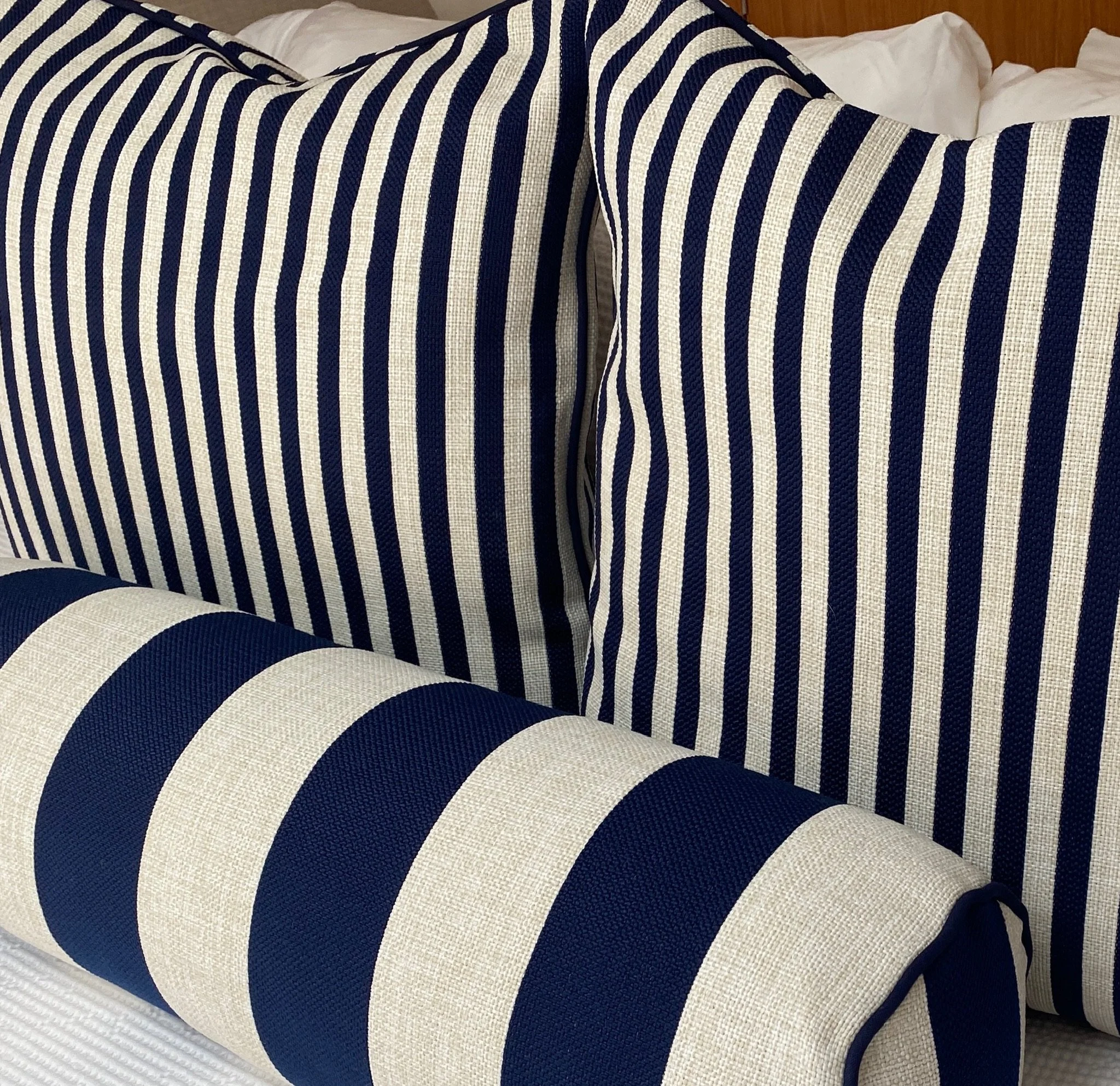 Close-up of a bed with striped navy blue and white bedding, including pillows and a blanket.