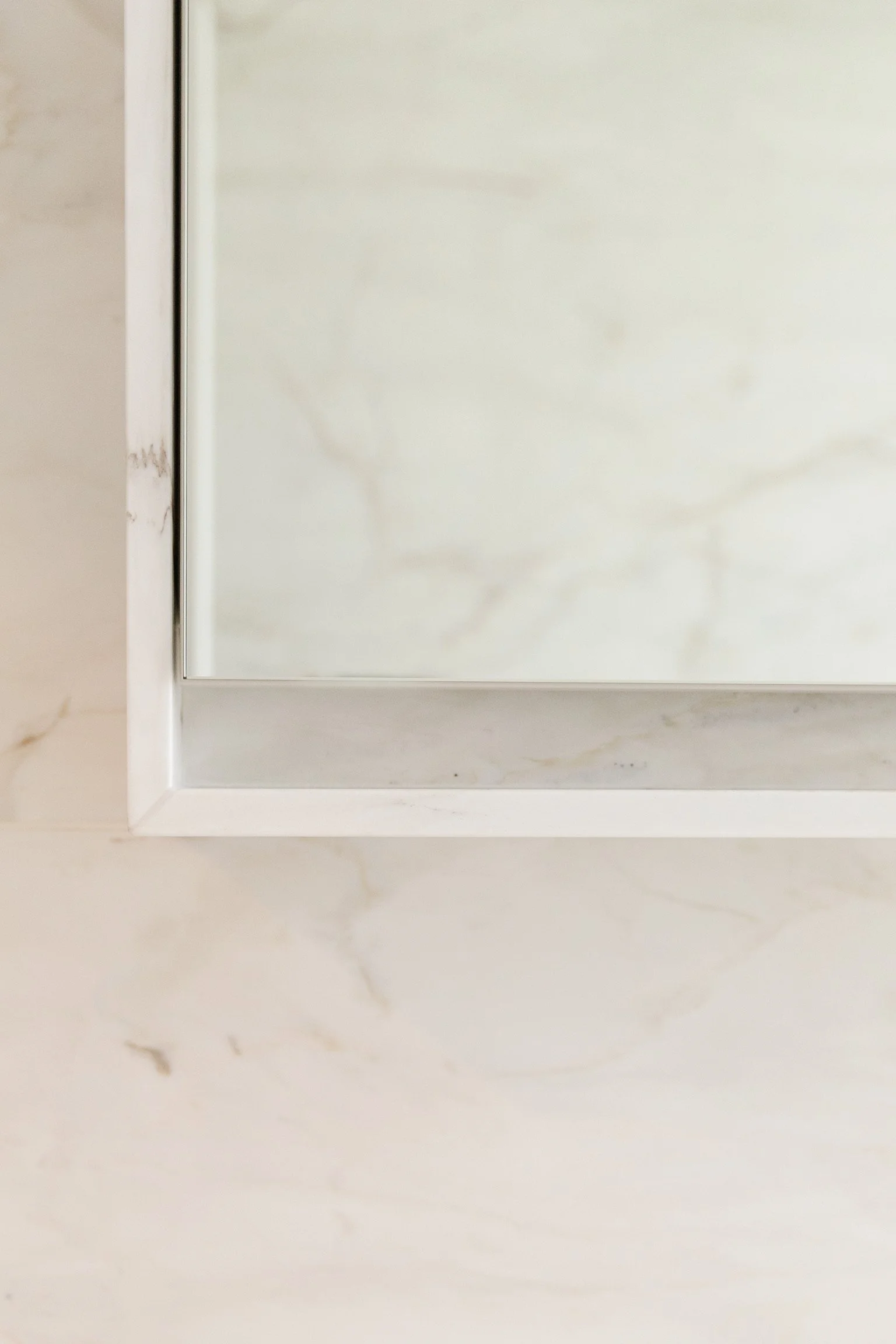 Close-up of a white or light-colored cabinet door with a metallic handle on the left side, mounted on a wall or surface with a marble or stone pattern.