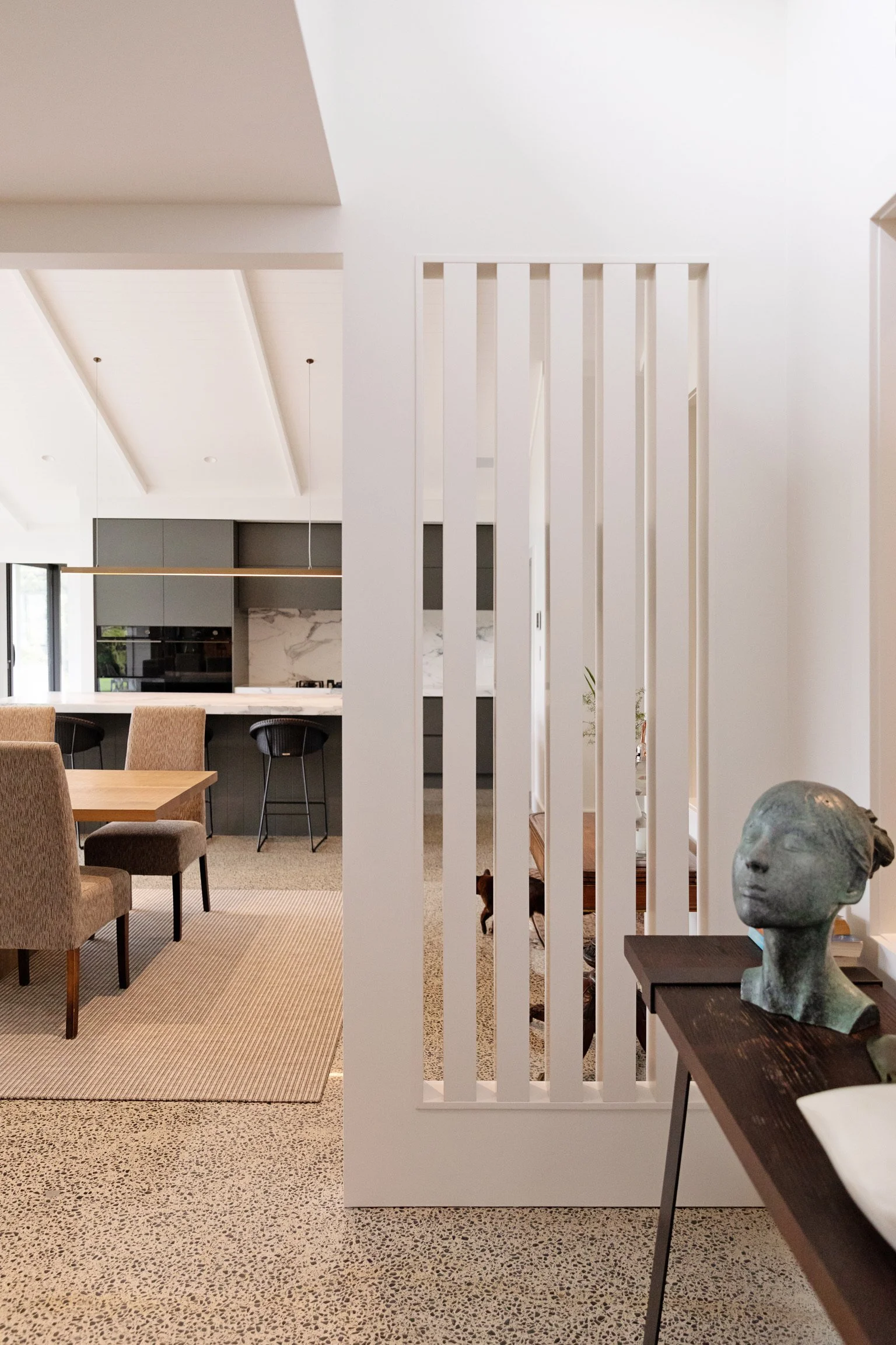 Modern open-concept kitchen and dining area with bar stools, neutral tones, and minimalist decor.