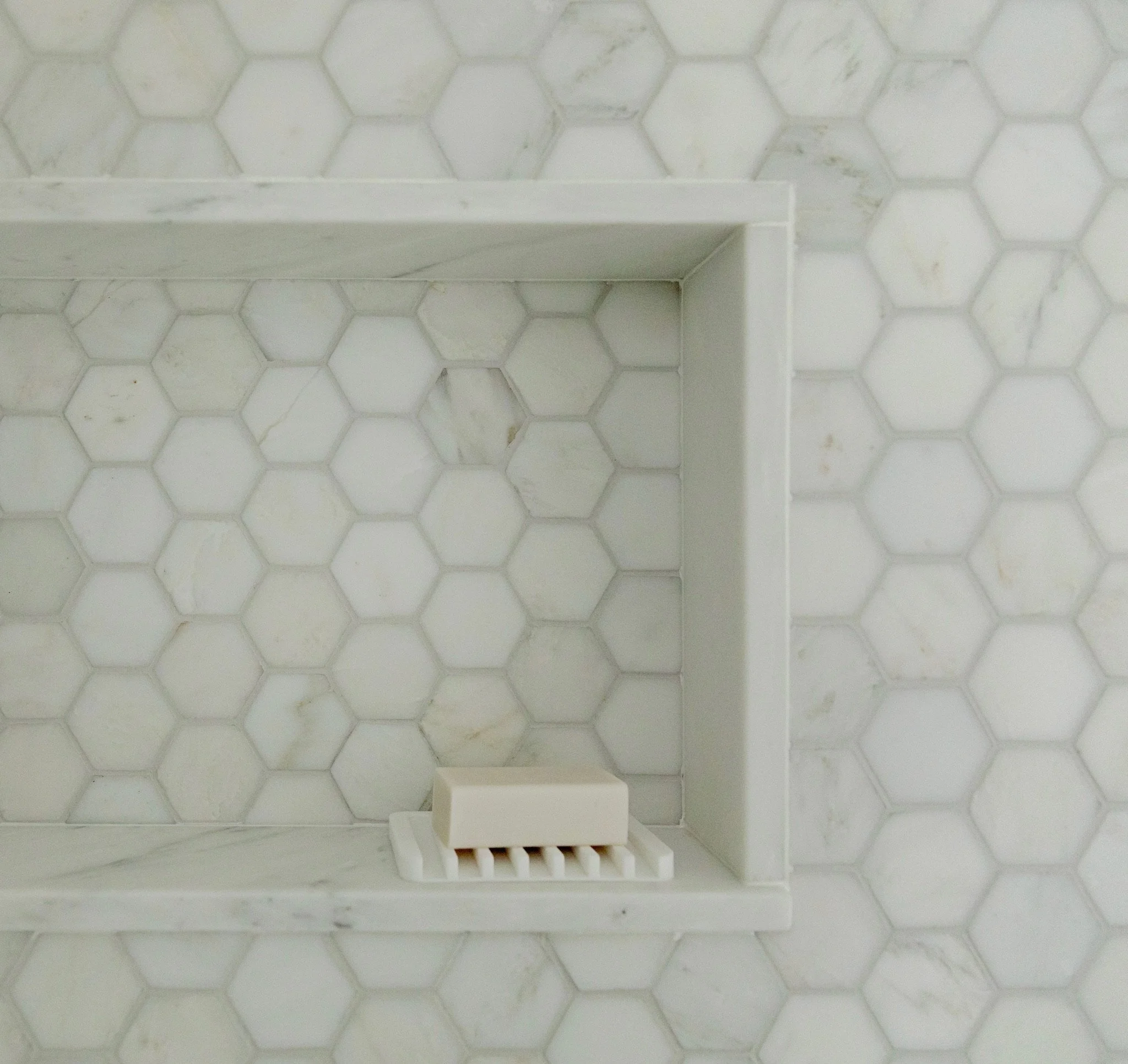 White plastic shelving unit on a hexagon marble tile floor.