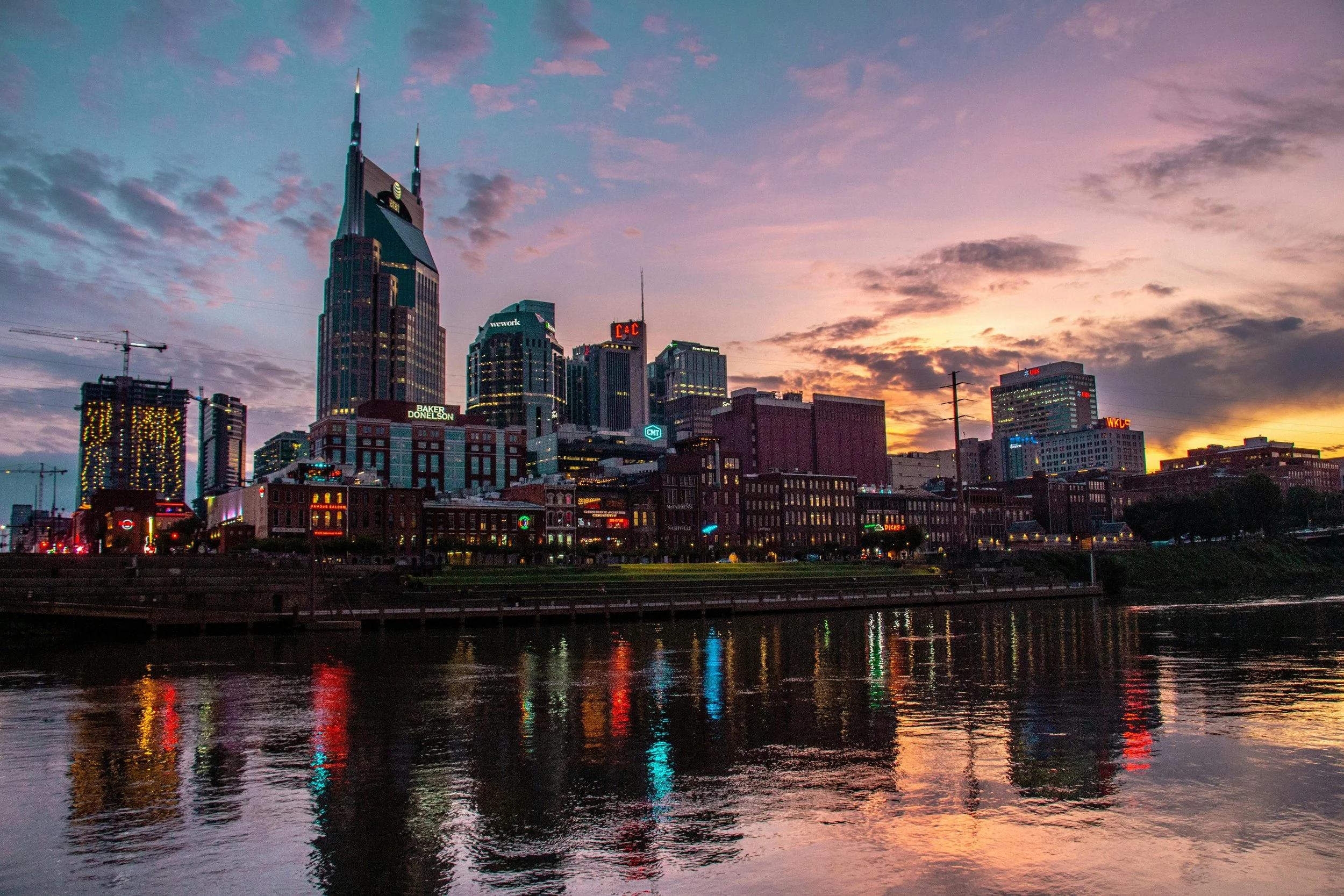 City skyline at sunset with tall skyscrapers and colorful reflections on the water.
