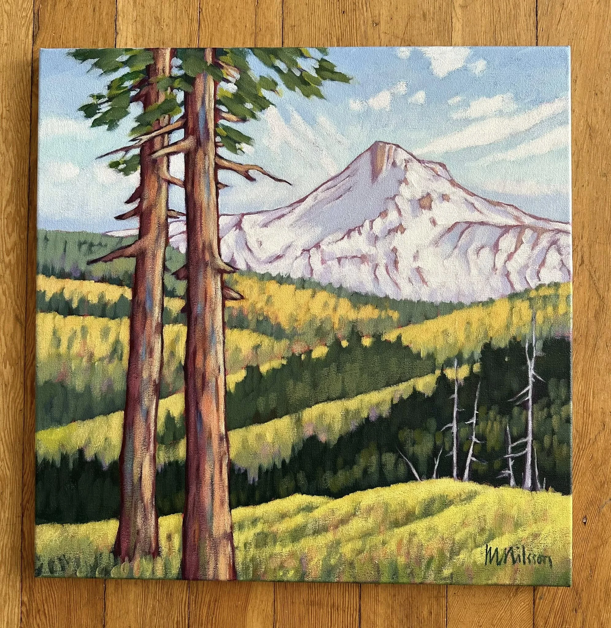 Landscape painting of a mountainous region with a snow-capped mountain in the background, evergreen trees in the foreground, and rolling green hills with patches of yellow. The sky is blue with clouds.Mark Nilsson ©