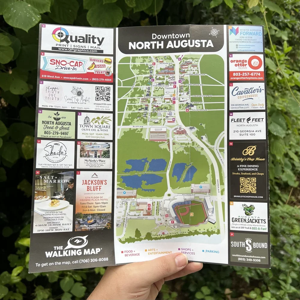 Map of downtown North Augusta showing streets, parks, and local businesses with advertisements and a legend for food, arts, shops, services, and parking.