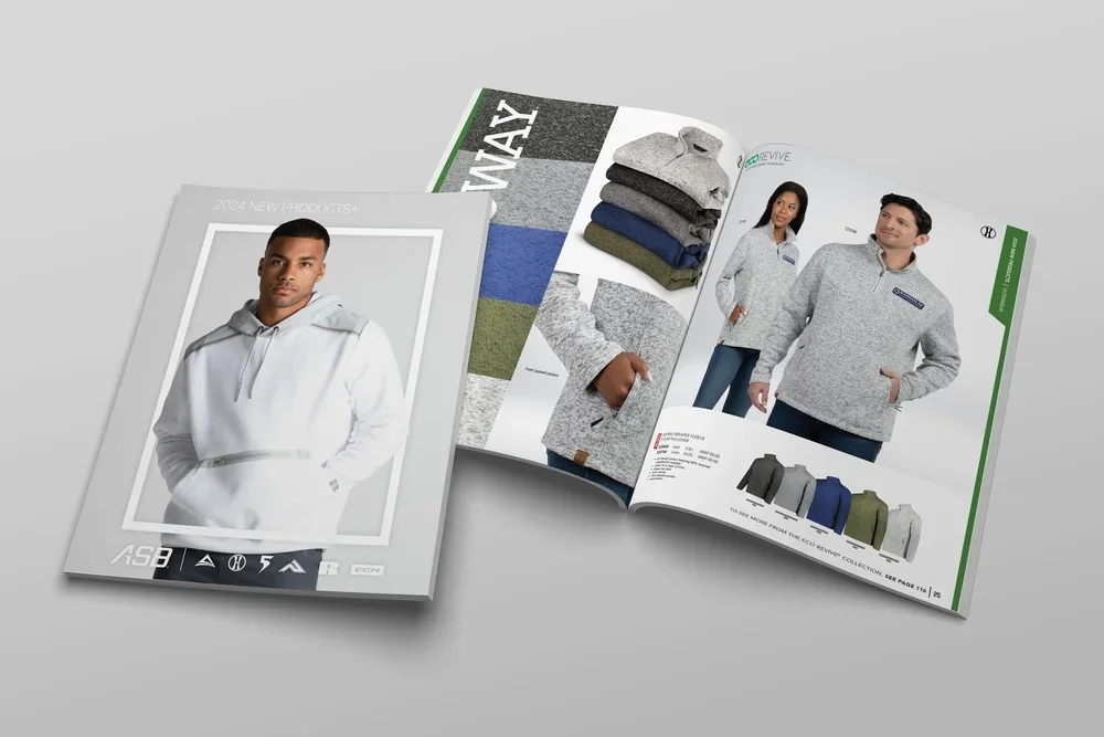 Open clothing catalog with folded shirts and models wearing gray zip-up sweatshirts