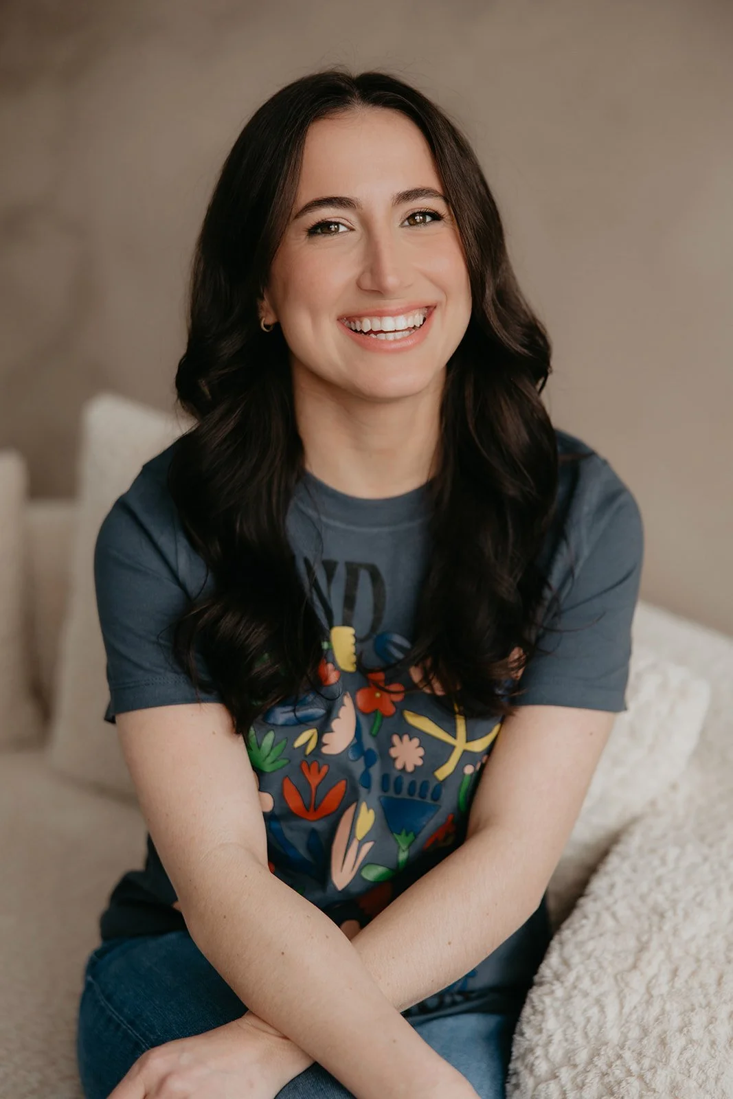 Lauren, a pediatric speech-language pathologist and founder of Shared Spark Pediatric Therapy, smiling for her 'Meet Your Therapist' bio. She is pictured in a navy blue t-shirt against a warm, neutral background in her Pittsburgh-based practice.