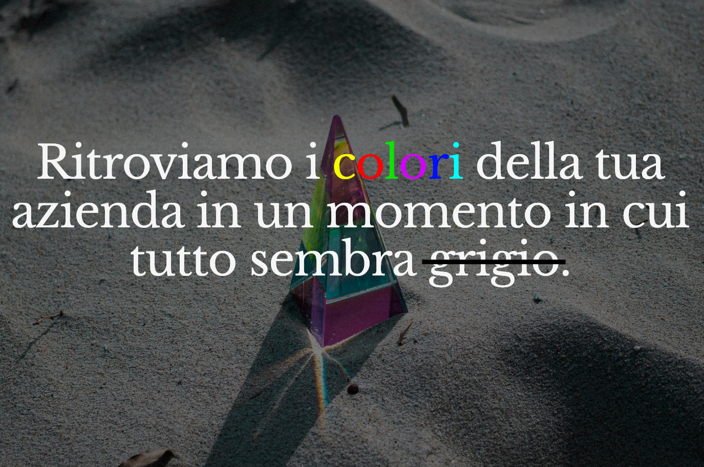 Un prisma colorato sulla sabbia con testo che dice: "Ritroviamo i colori della tua azienda in un momento in cui tutto sembra grigio".