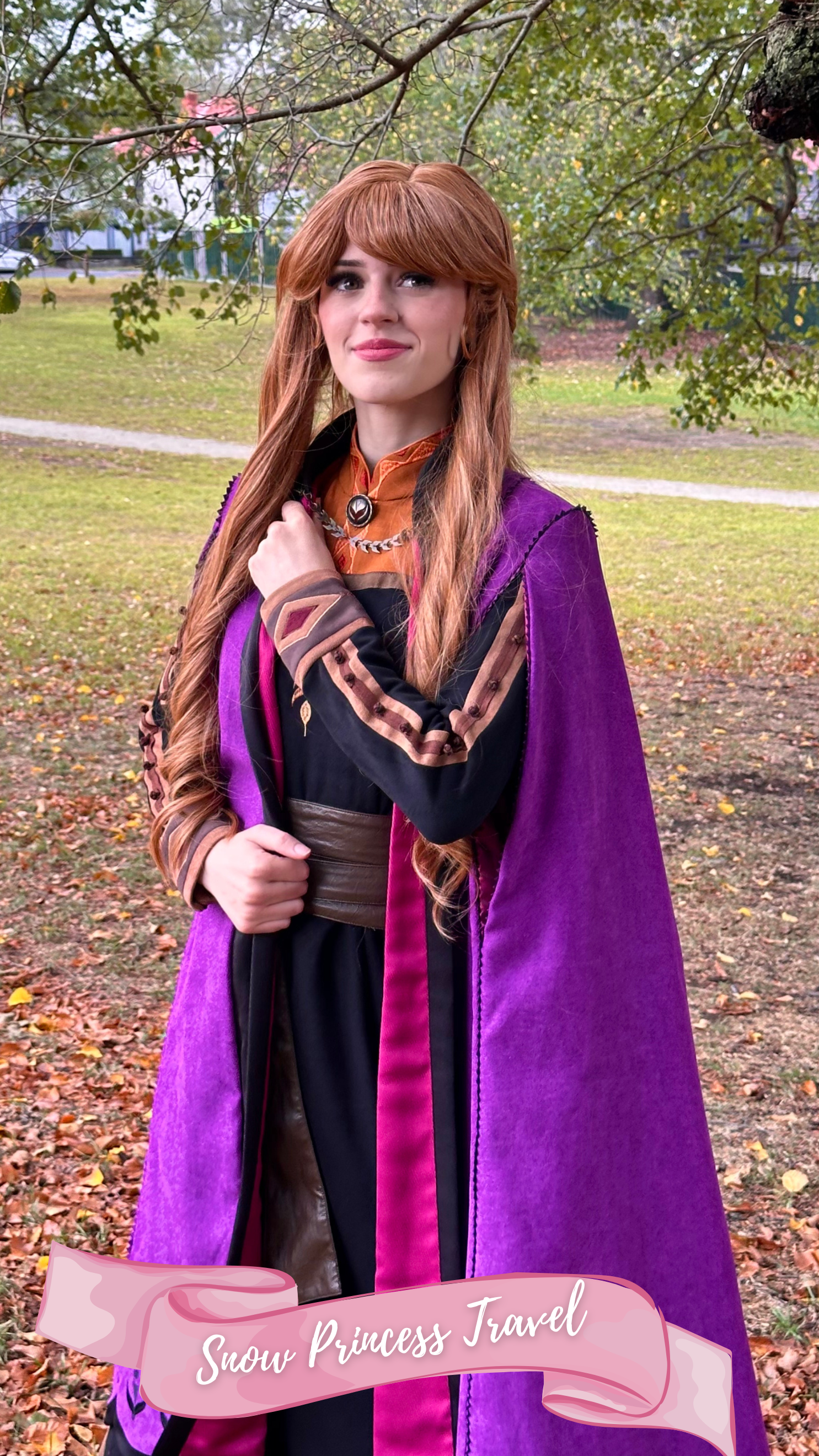 A woman dressed as the princess from the fairy tale Frozen, wearing a purple cape,brown and white dress with her long ginger hair down, standing outdoors on grass with trees in the background.
