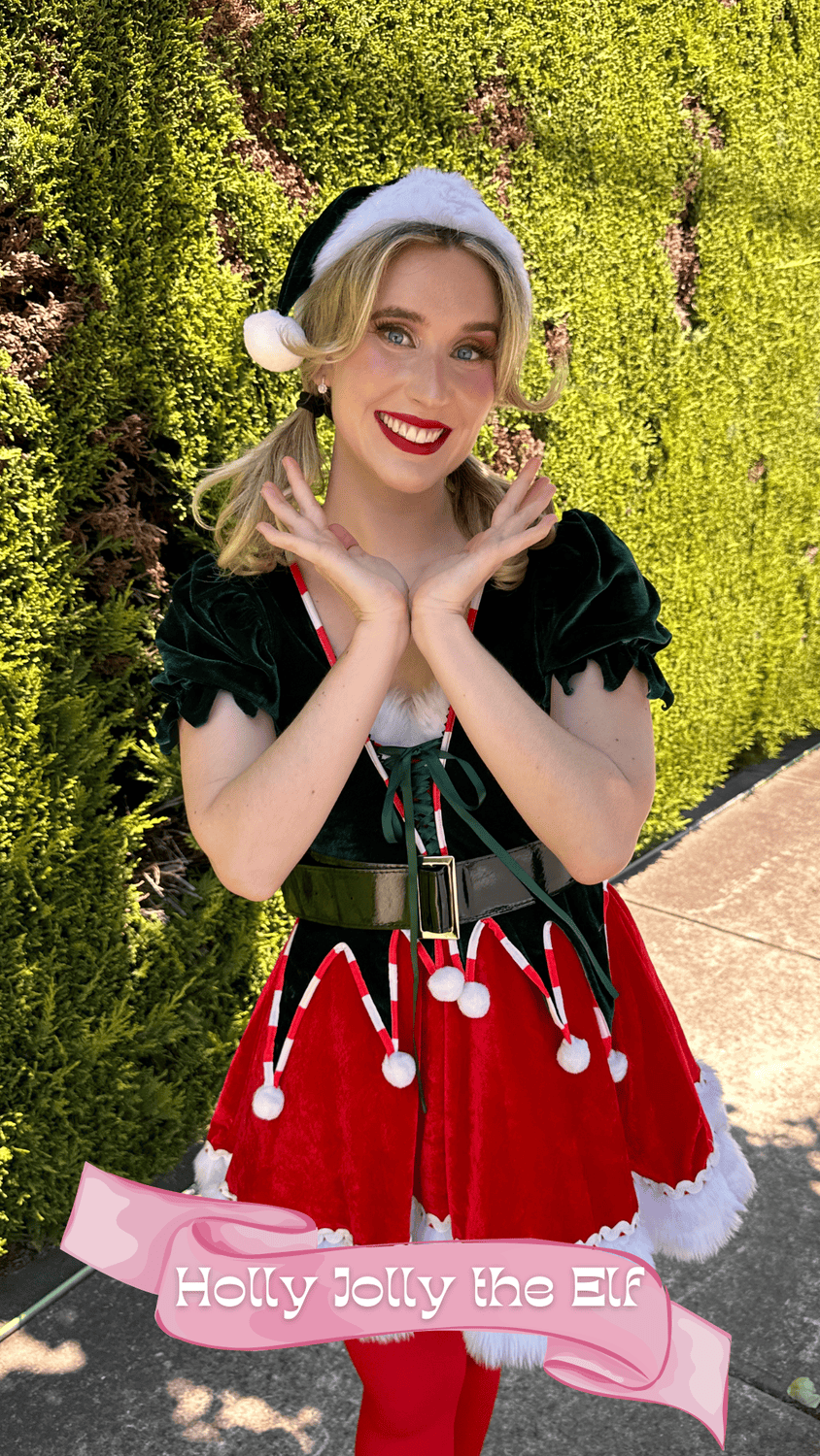 A young woman smiling in a festive holiday outfit with a Santa hat, green velvet top, red skirt with white trimmings, red tights, standing outdoors in front of a green hedge. The bottom of the image features a pink banner with the text 'Holly Jolly t