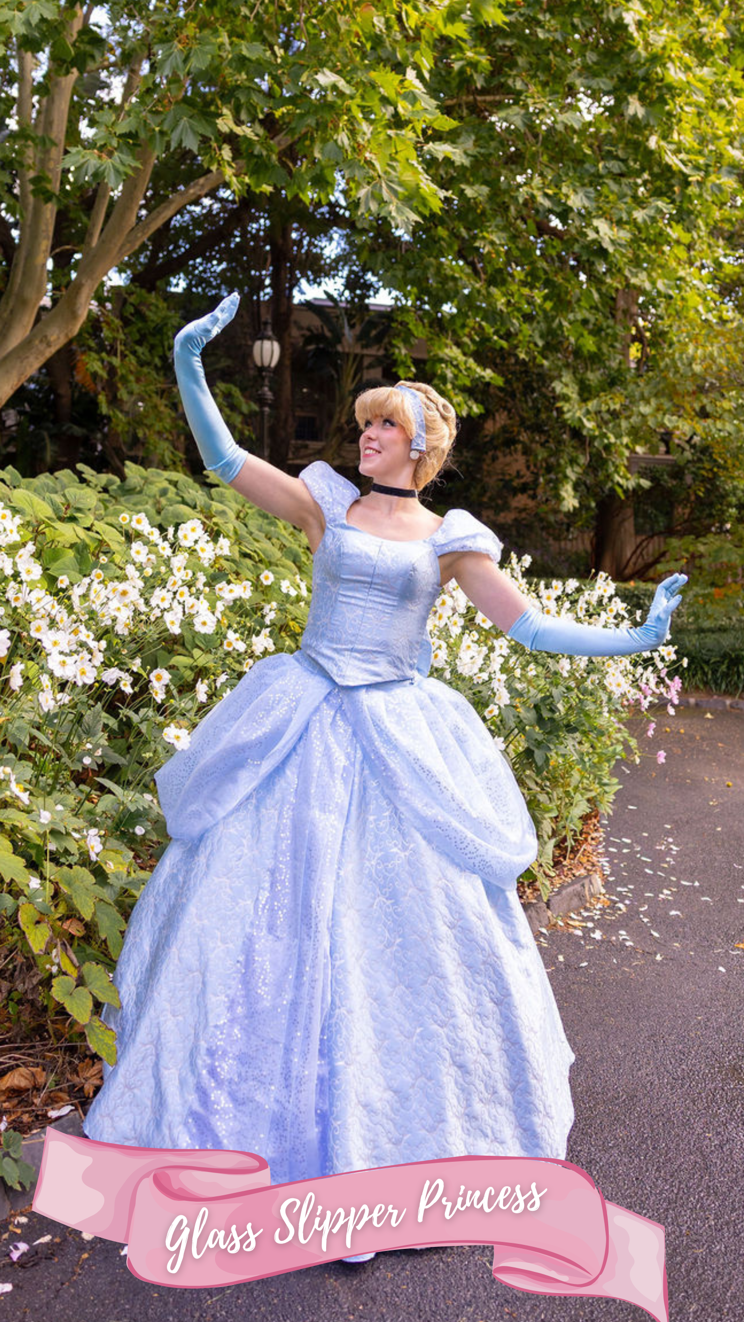 Woman dressed as a princess in a blue gown, standing on stairs outside with greenery and a red door in the background, holding her chin with one hand and smiling. A pink banner at the bottom reads 'Glass Slipper Princess'.
