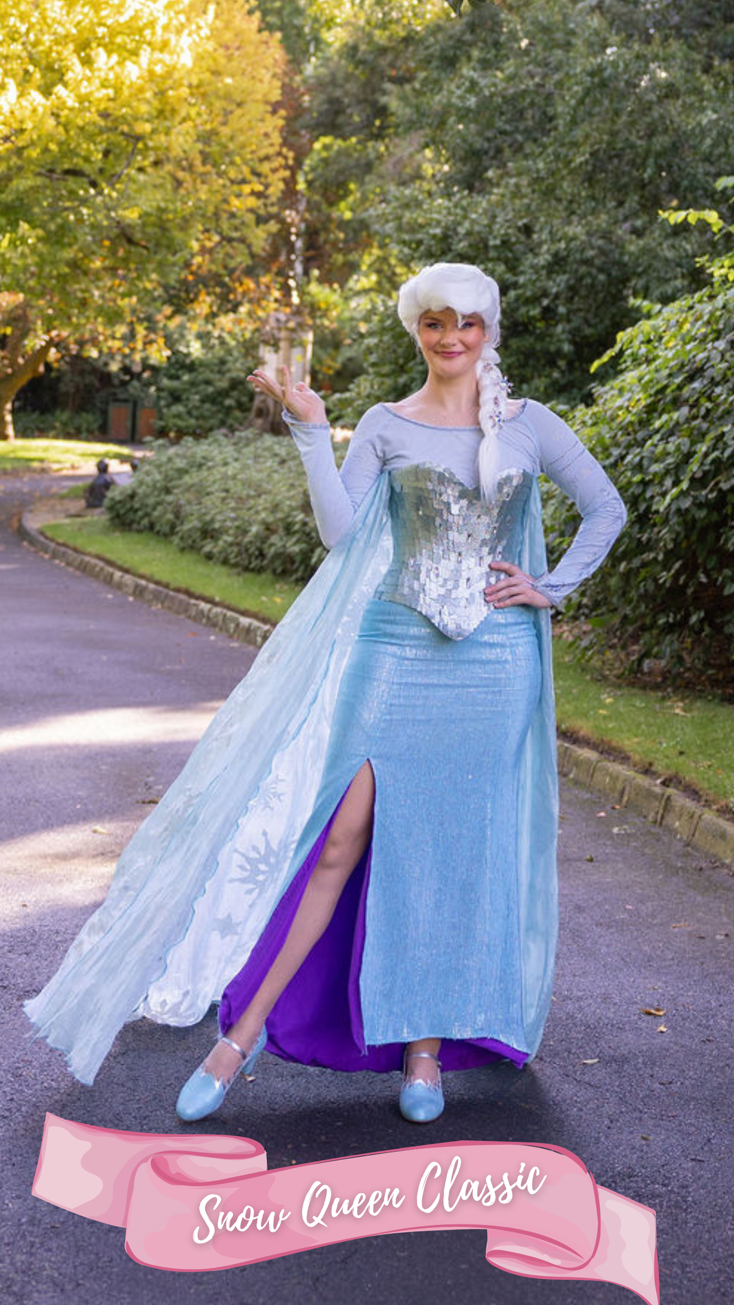 A woman dressed as the princess from the fairy tale Frozen, wearing a blue skirt, blue top, sparkly corset with snowflakes in her white hair, standing outdoors on a path with trees in the background.