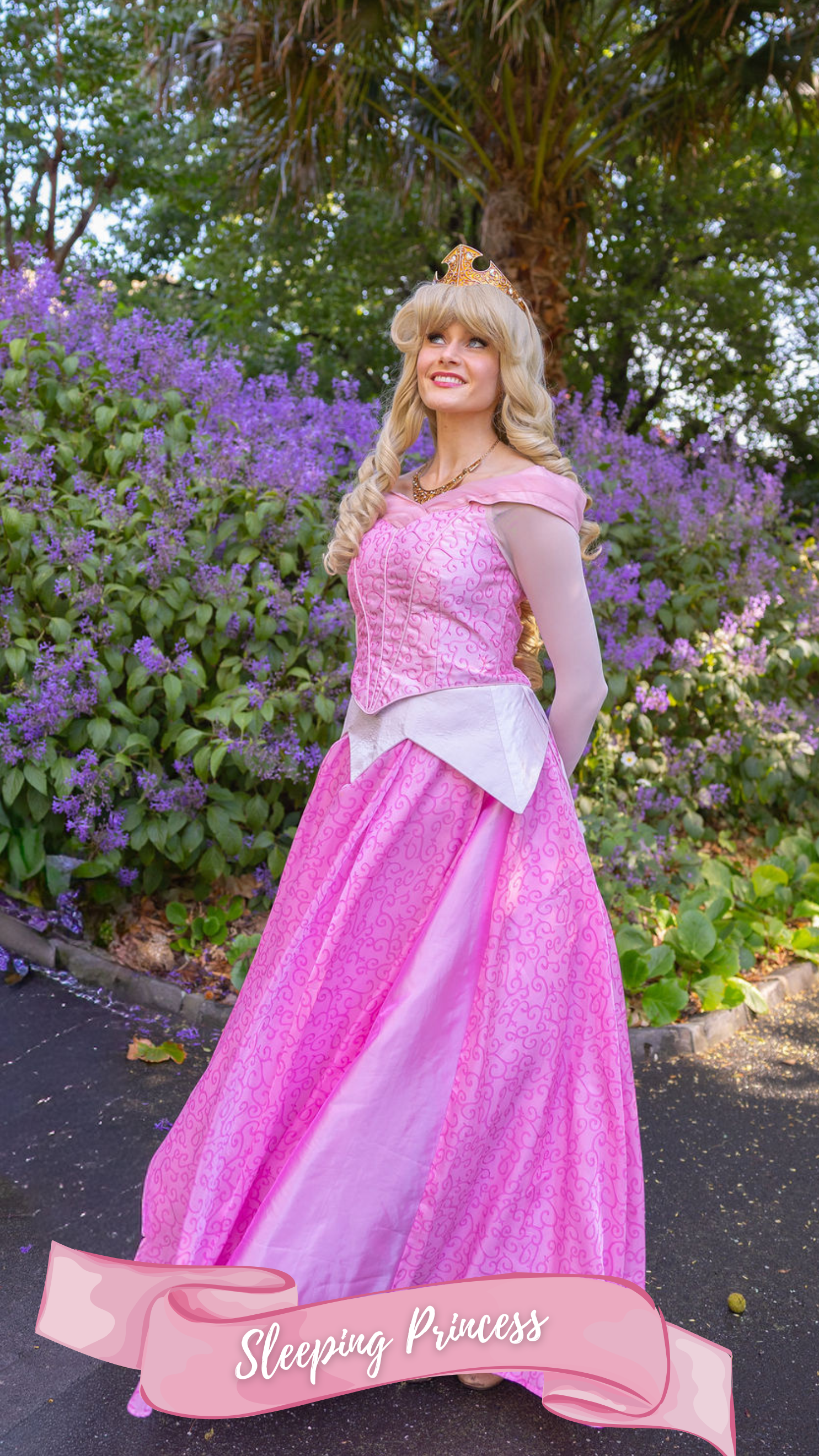 A woman dressed as a princess in a pink gown with a crown, standing in front of purple flowers, with the words 'Sleeping Princess' on a pink banner at the bottom.