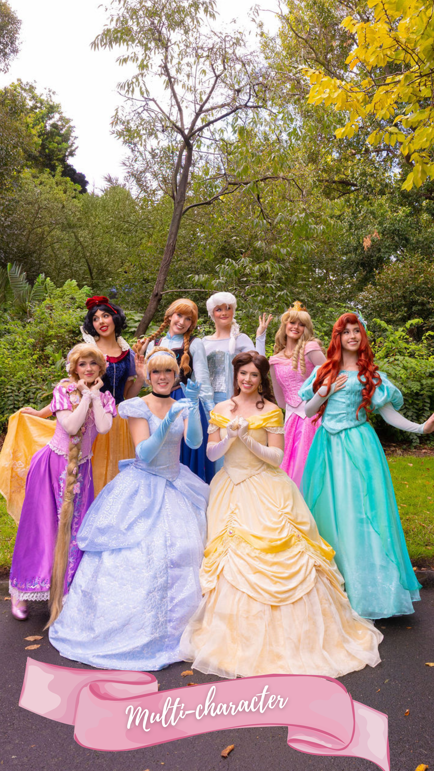 Multiple women dressed as princesses smile and pose in outdoor group photo
