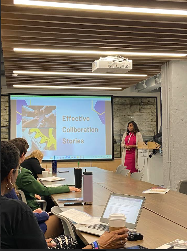 Christa Wheeler speaking at a professional workshop on effective collaboration in a conference setting with attendees engaged in learning, note taking, and discussion
