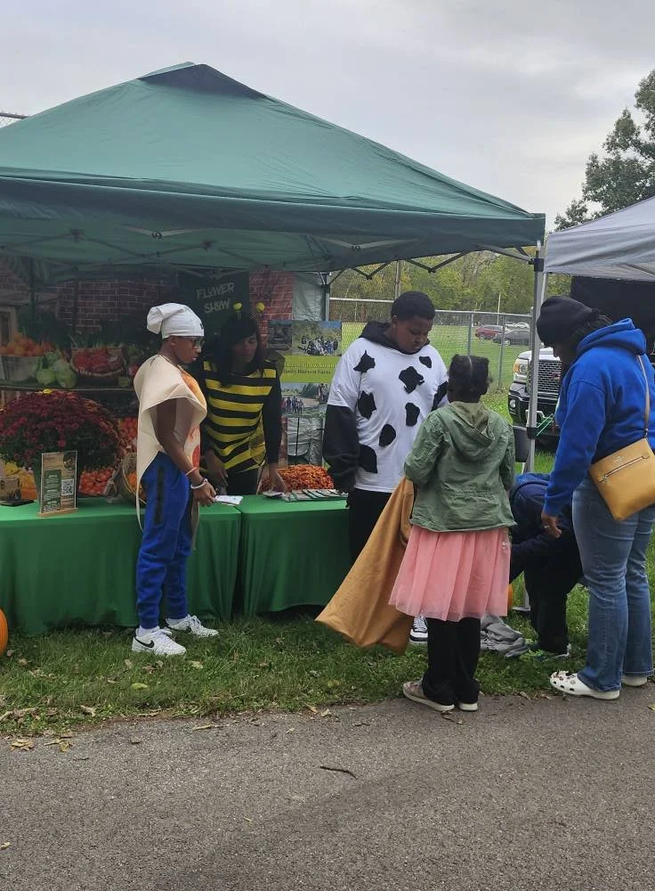 Community members visiting an Efinity Harvest Farm booth at an outdoor event in Trotwood, Ohio, engaging with fresh produce and promoting local agriculture and food access