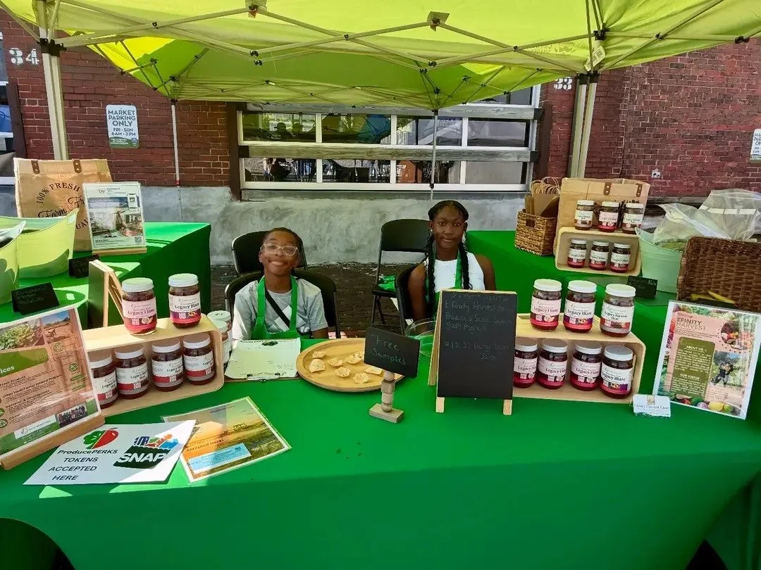 Efinity Harvest Farm youth team at a local farmers market booth displaying fresh produce and value added products, offering samples and promoting SNAP access, healthy eating, and community food systems in Ohio