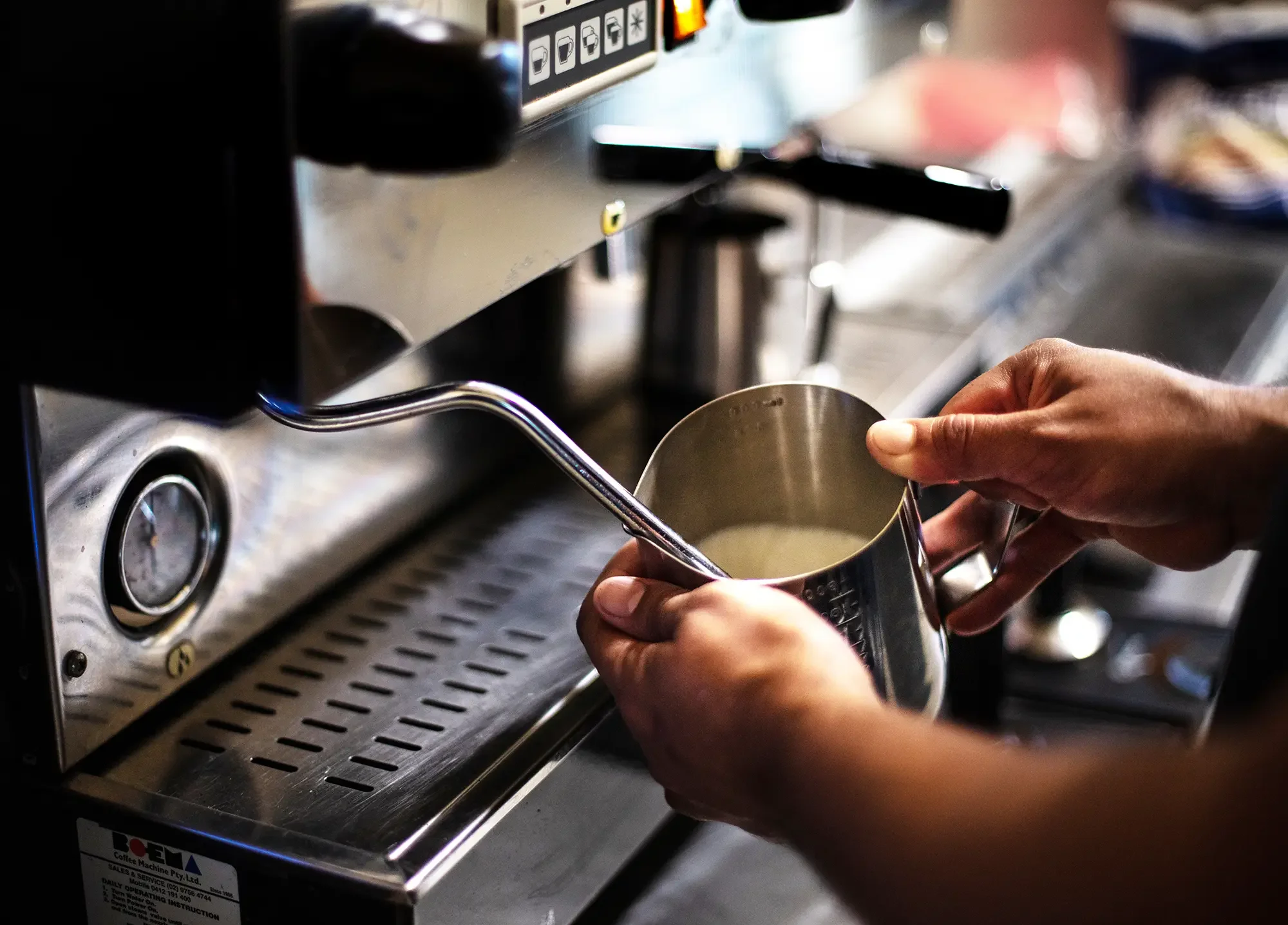 hands holding a milk jug under a milk wand steaming milk