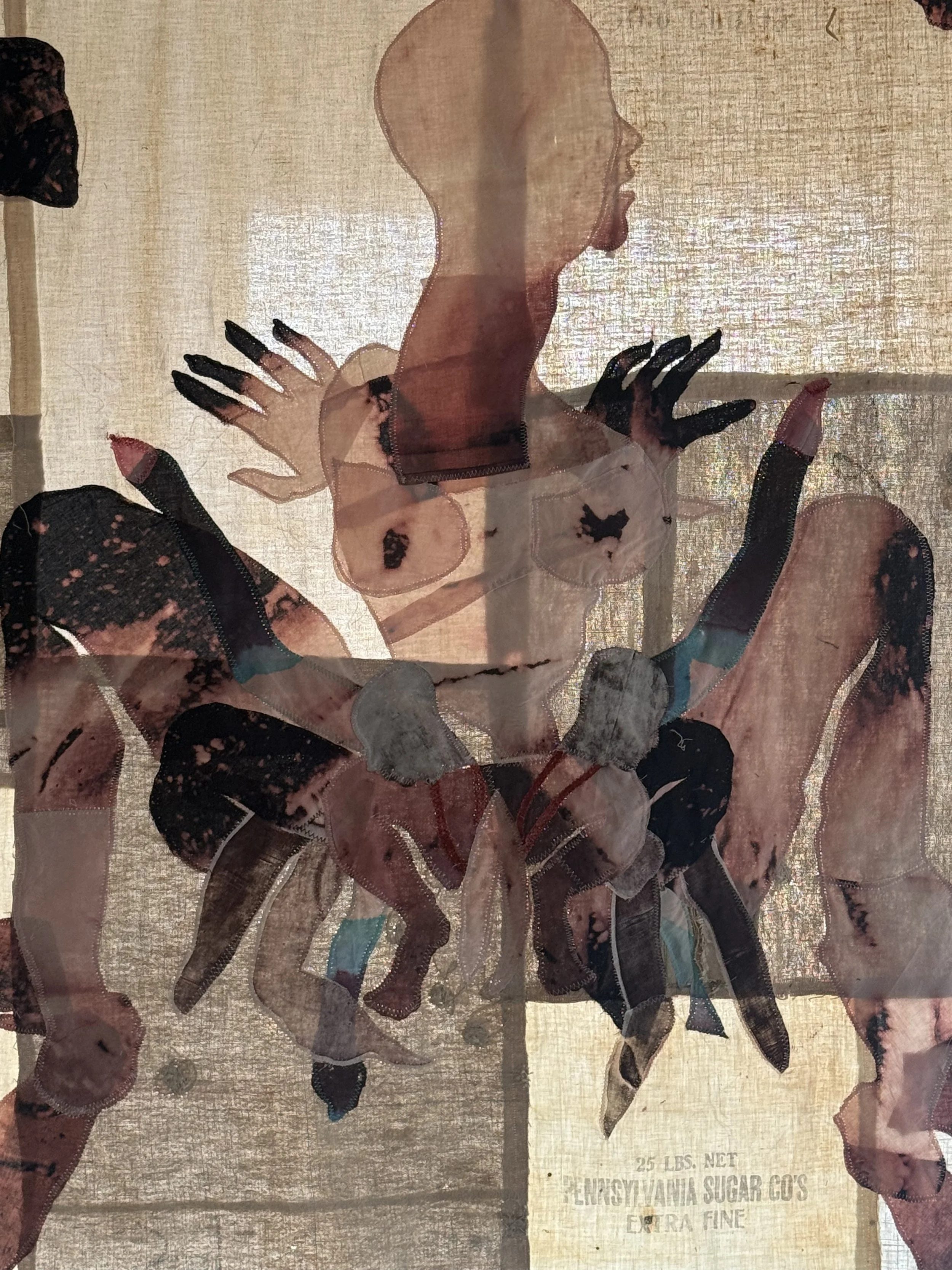 "Cecilia" (2026) (detail, in afternoon light) 70" x 57" Bleached bedsheets, coffee, fluid watercolor, relief prints, used feed, seed and soap sacks, hand embroidery