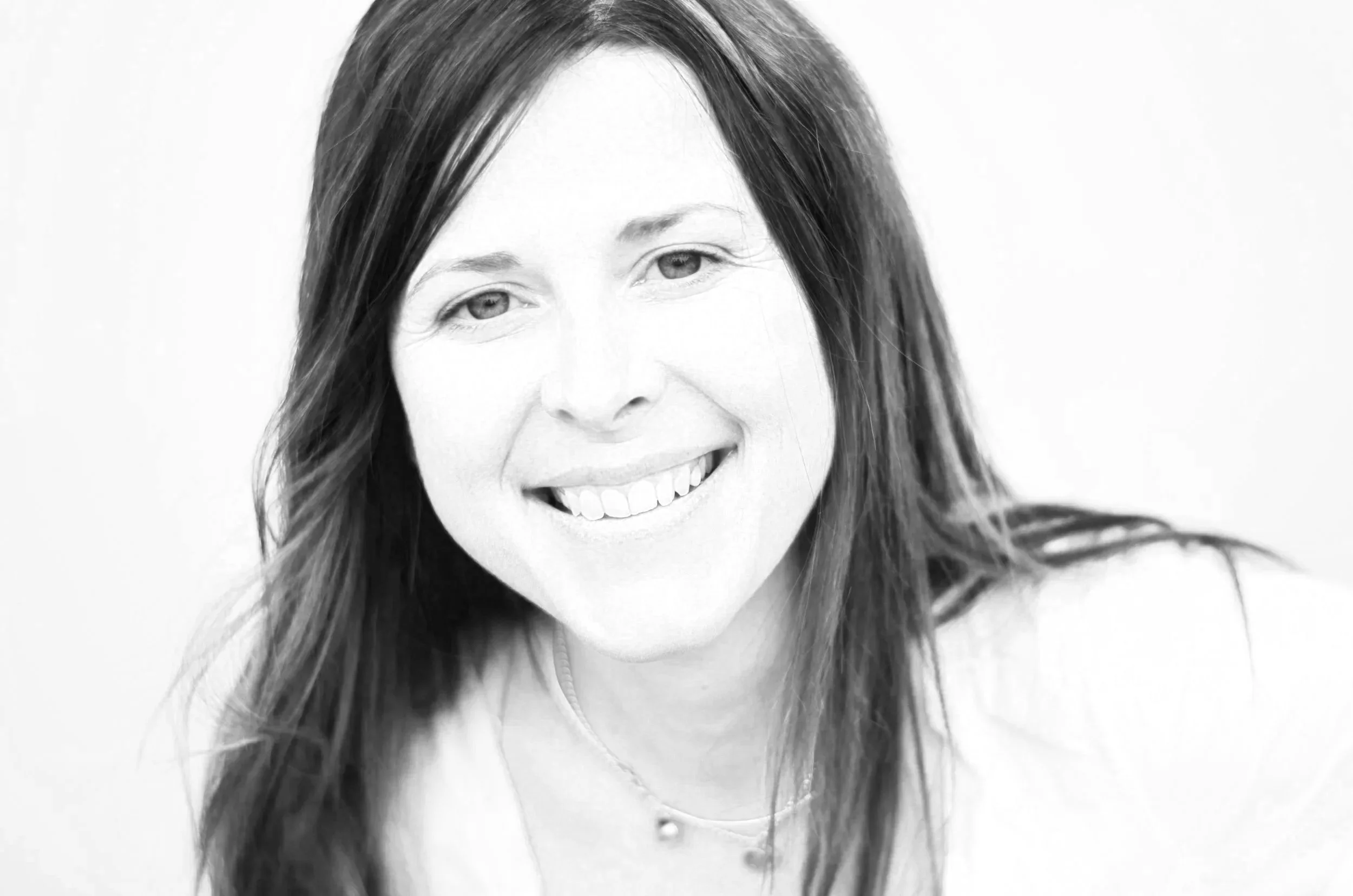 Black and white portrait of a smiling woman with long dark hair, looking slightly to the side.