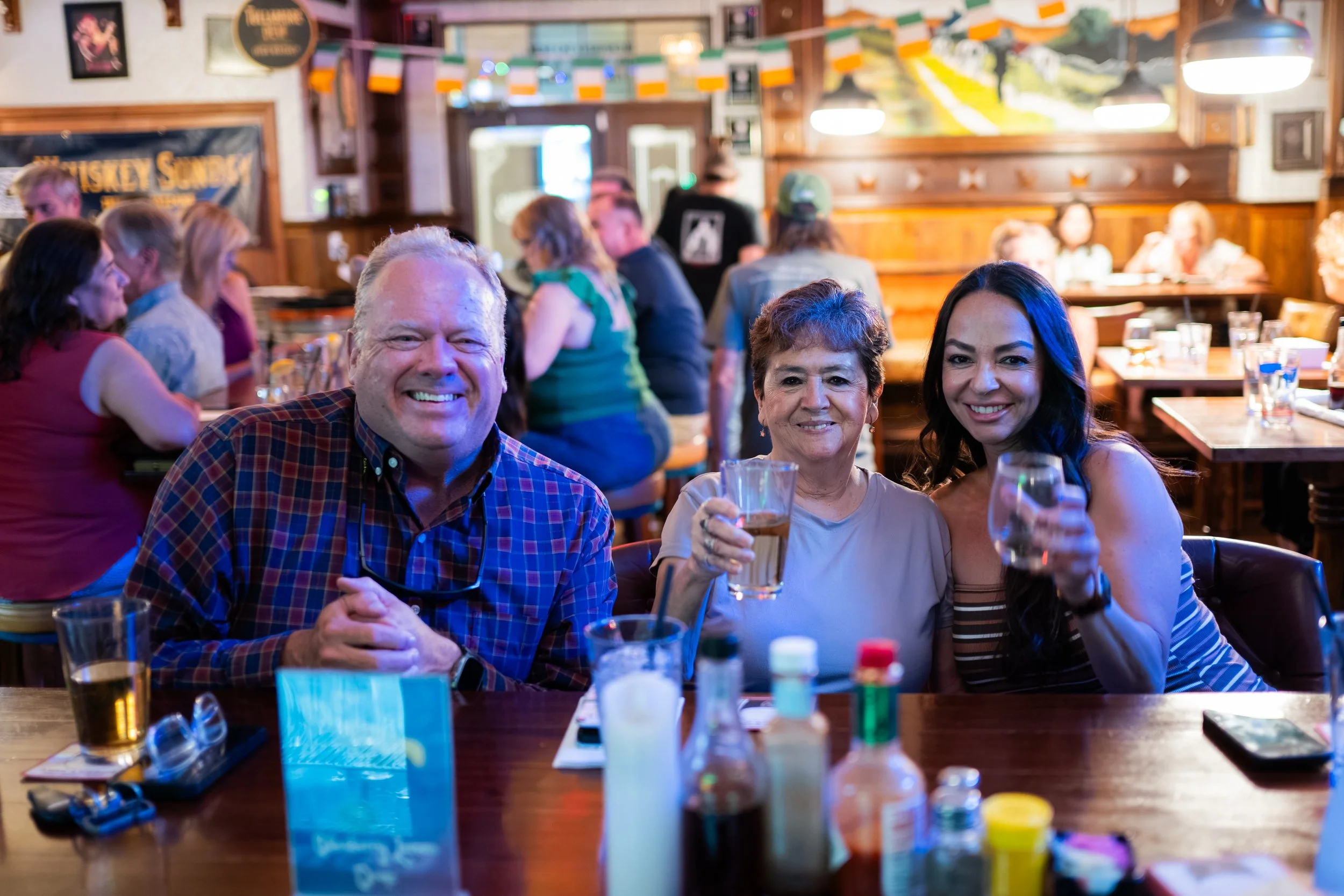 People enjoying drinks at a lively bar or restaurant with Irish decorations.