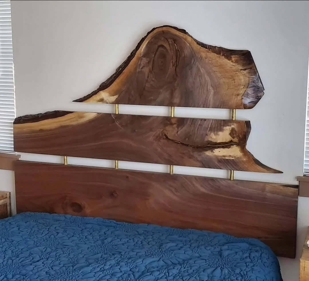 A bed with a headboard made from large, natural wood slabs featuring white, cylindrical rods with gold accents.