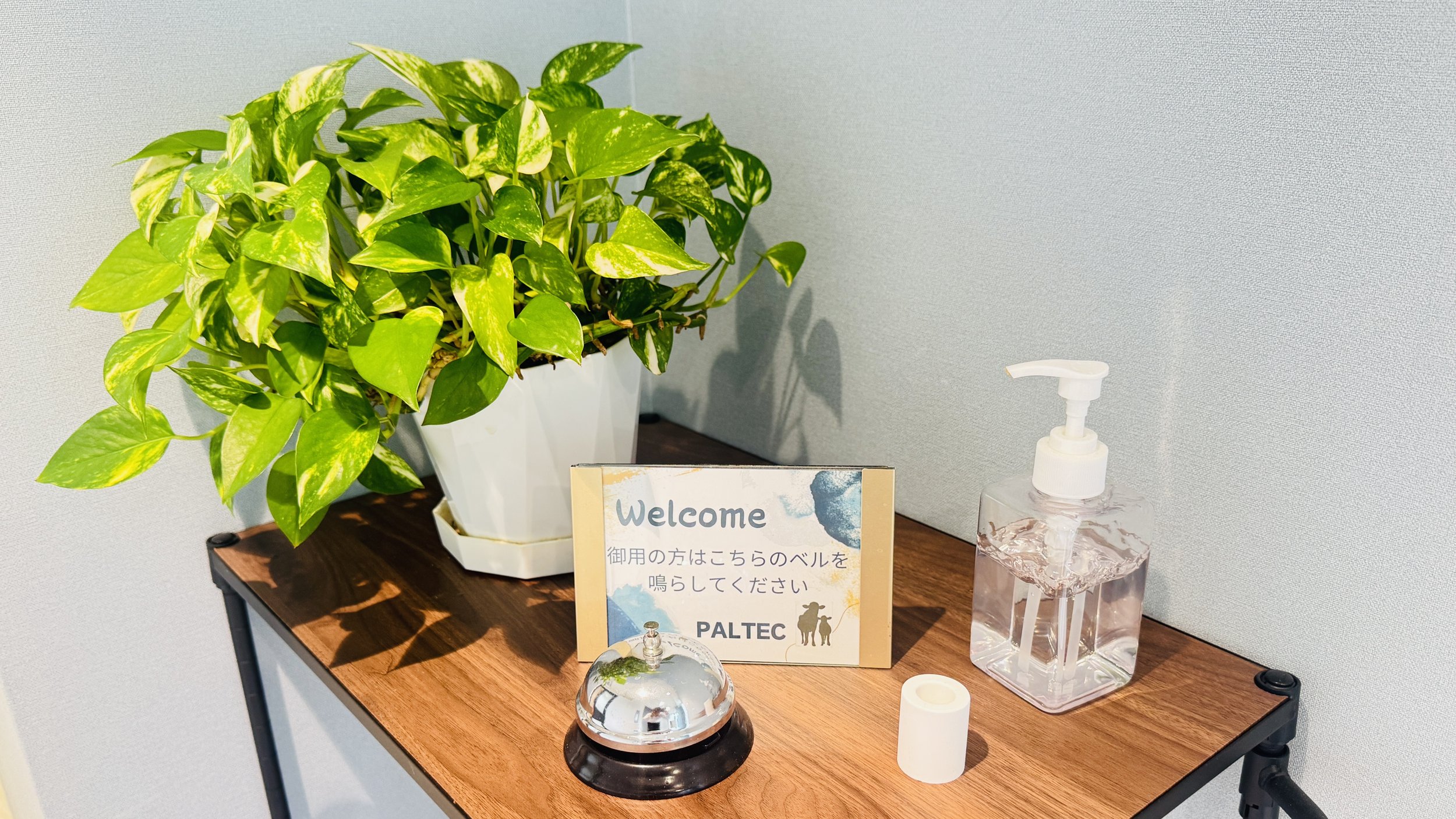 観葉植物とハンドソープの容器、ウェルカムカードが置かれた木製テーブル