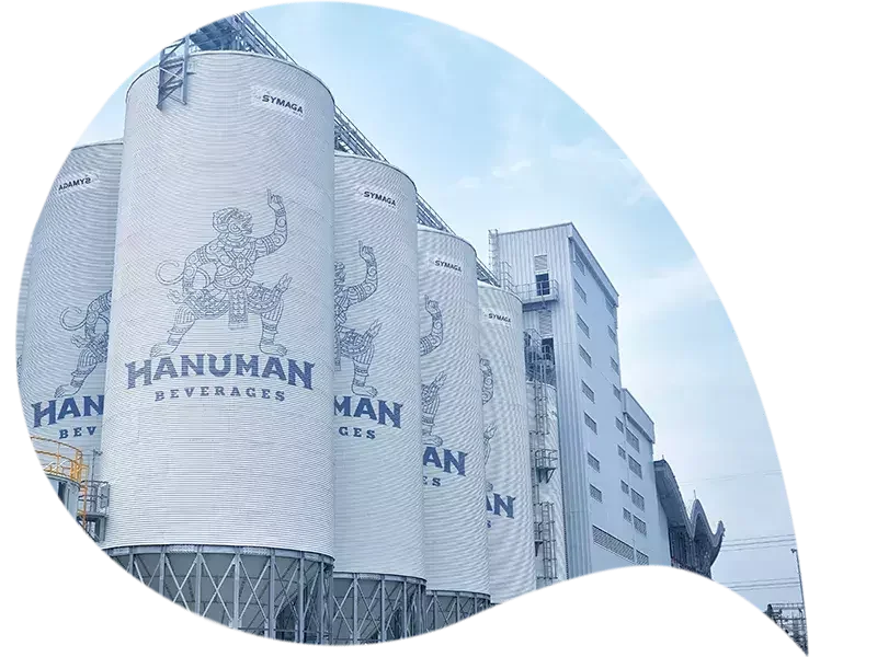 巨大な建物の壁に「HANUMAN BEVERAGES」と書かれた看板と、猿の神様のイラストが描かれている。