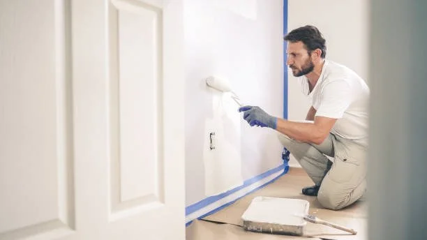 Man painting a wall with a paint roller in a room.