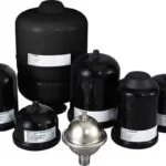 Collection of black cosmetic containers and bottles, with a small silver jar in the center.