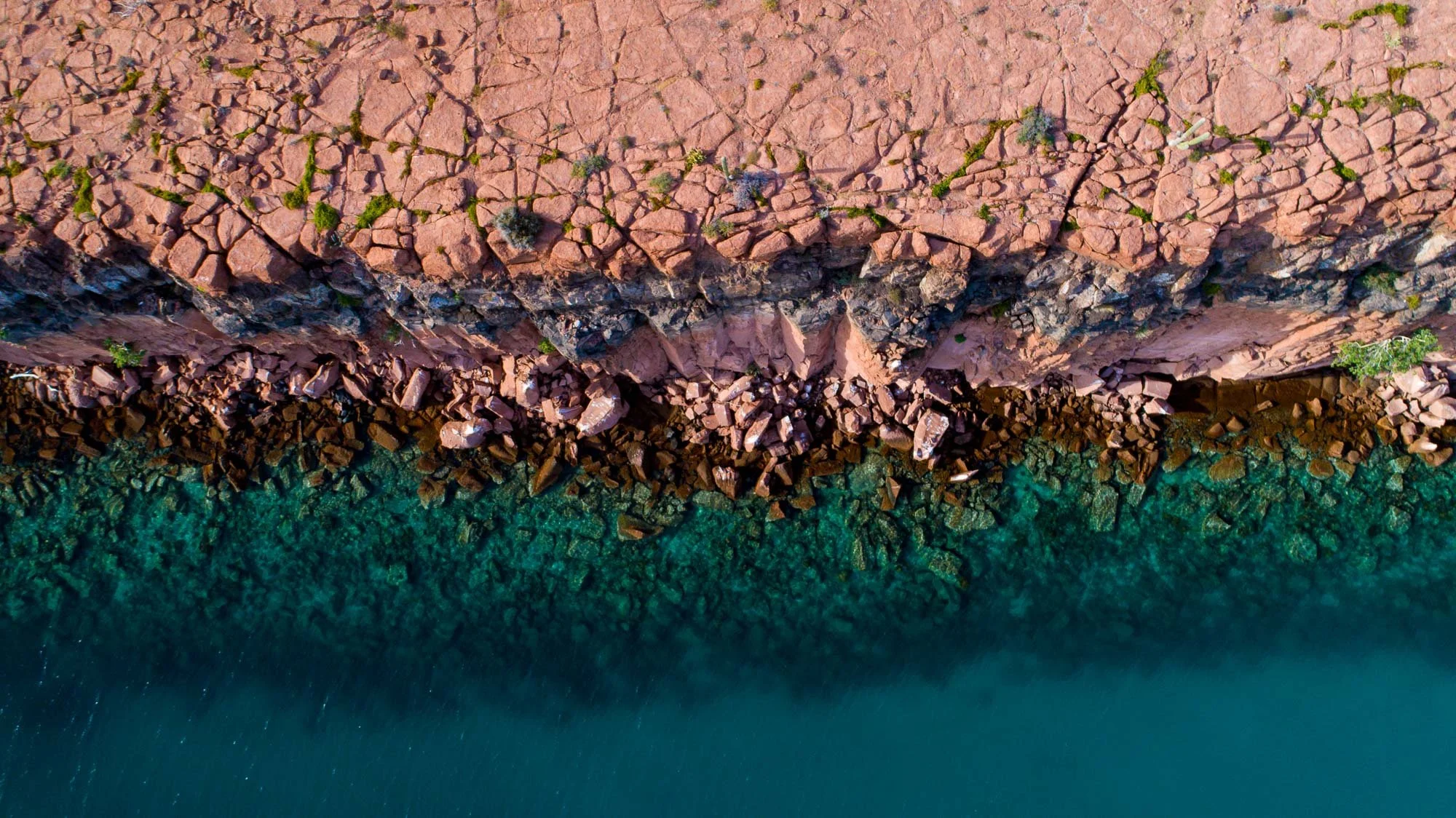 Una de mis favoritas. Desde el aire, la península se despliega en capas horizontales perfectas: arriba, los ocres profundos de la roca; abajo, los azules intensos del mar. No hay distracciones, solo color y forma en su máxima expresión.
Es la esencia