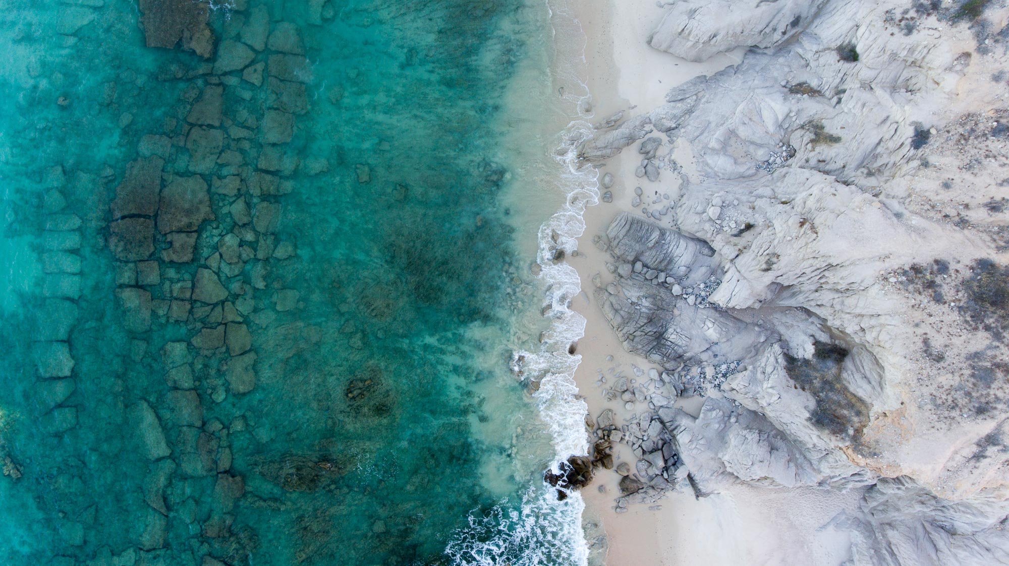 Desde el aire, el encuentro es brutal y limpio: el azul del mar se detiene en seco contra los ocres del desierto. No hay transición, solo contraste puro, como si dos mundos opuestos se tocaran por un instante.
Líneas simples, colores definidos y una 