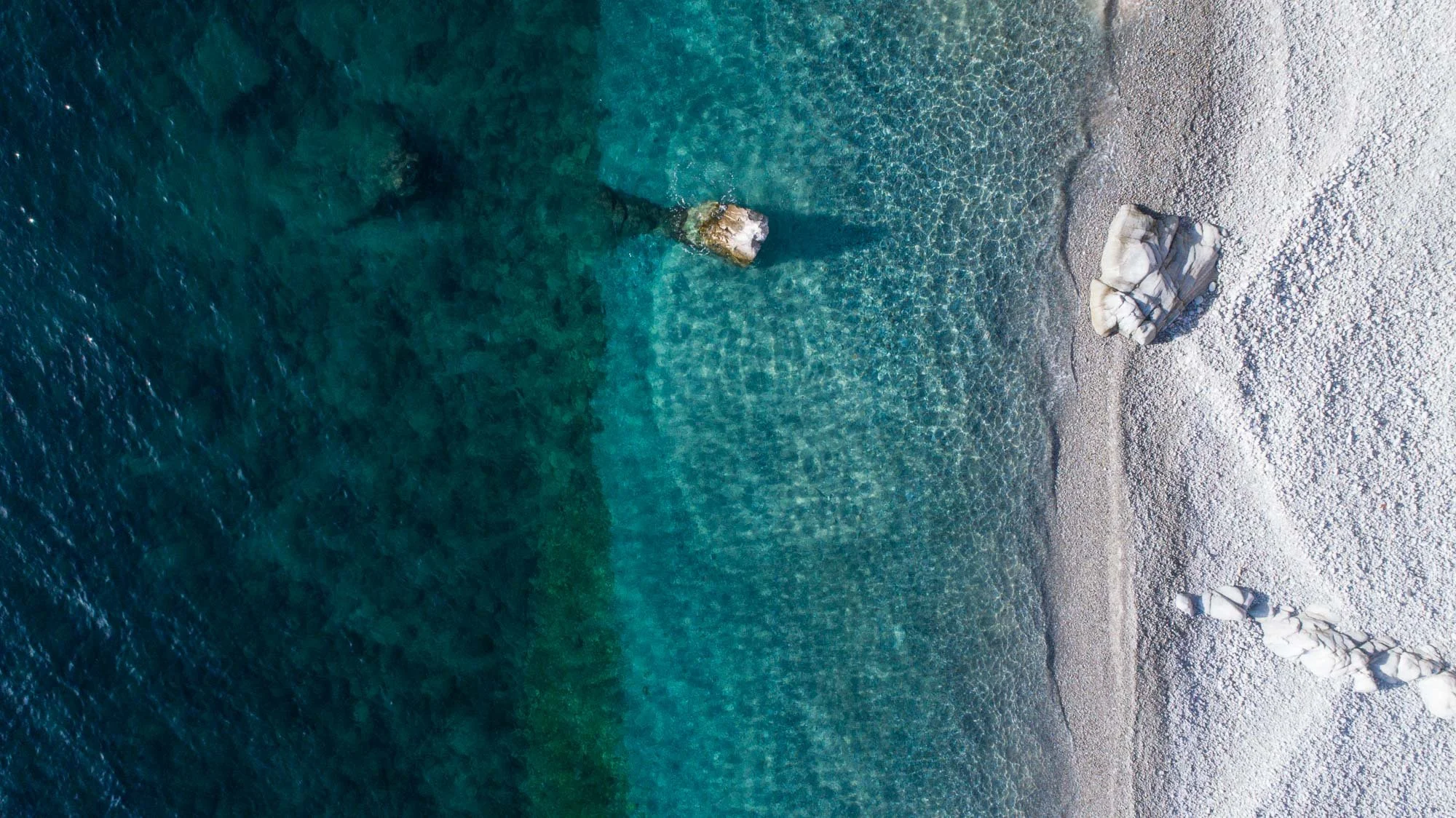 Tres franjas limpias, casi perfectas: el azul profundo, el turquesa de los arrecifes y la orilla rocosa marcando el límite.
Sin elementos de sobra, solo color, contraste y equilibrio en su forma más pura.