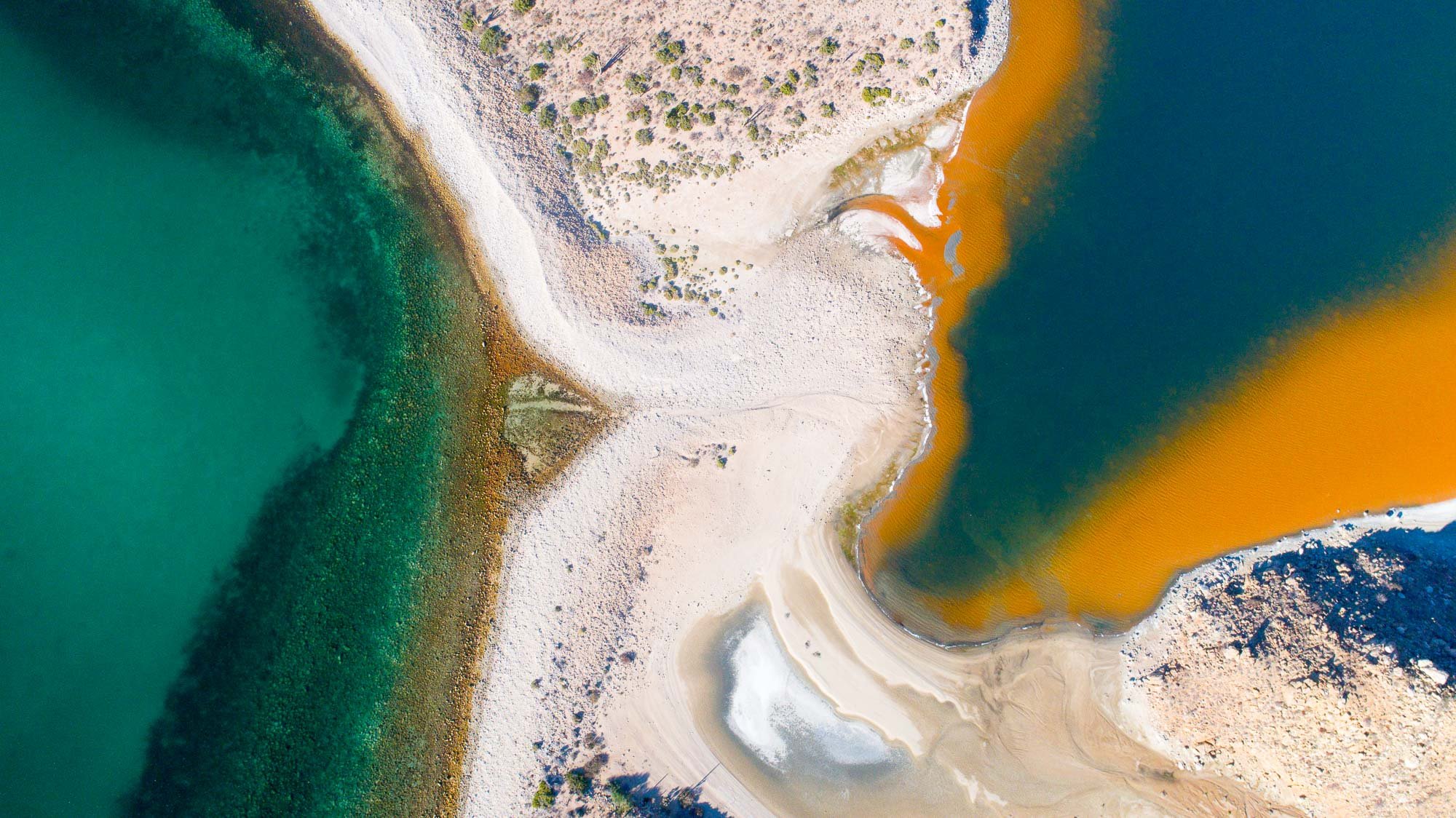 Una toma aérea transforma el encuentro entre el mar y una salina en una composición abstracta donde la realidad se vuelve patrón. El agua del Golfo de California entra en diálogo con las geometrías precisas de la salina: líneas rectas, bordes definid