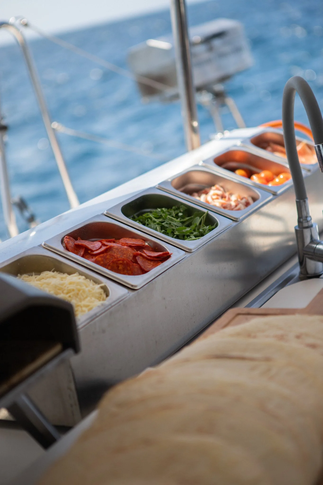 Estación de servicio con ingredientes y condimentos en bandejas en un barco, con agua y velas en el fondo.