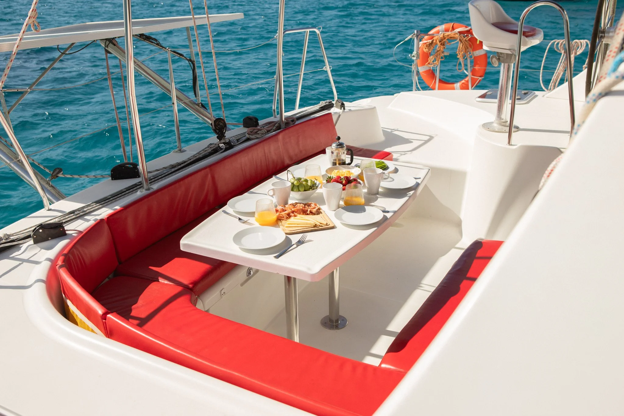 Comida y bebidas en una mesa en un yate, con vista al mar azul