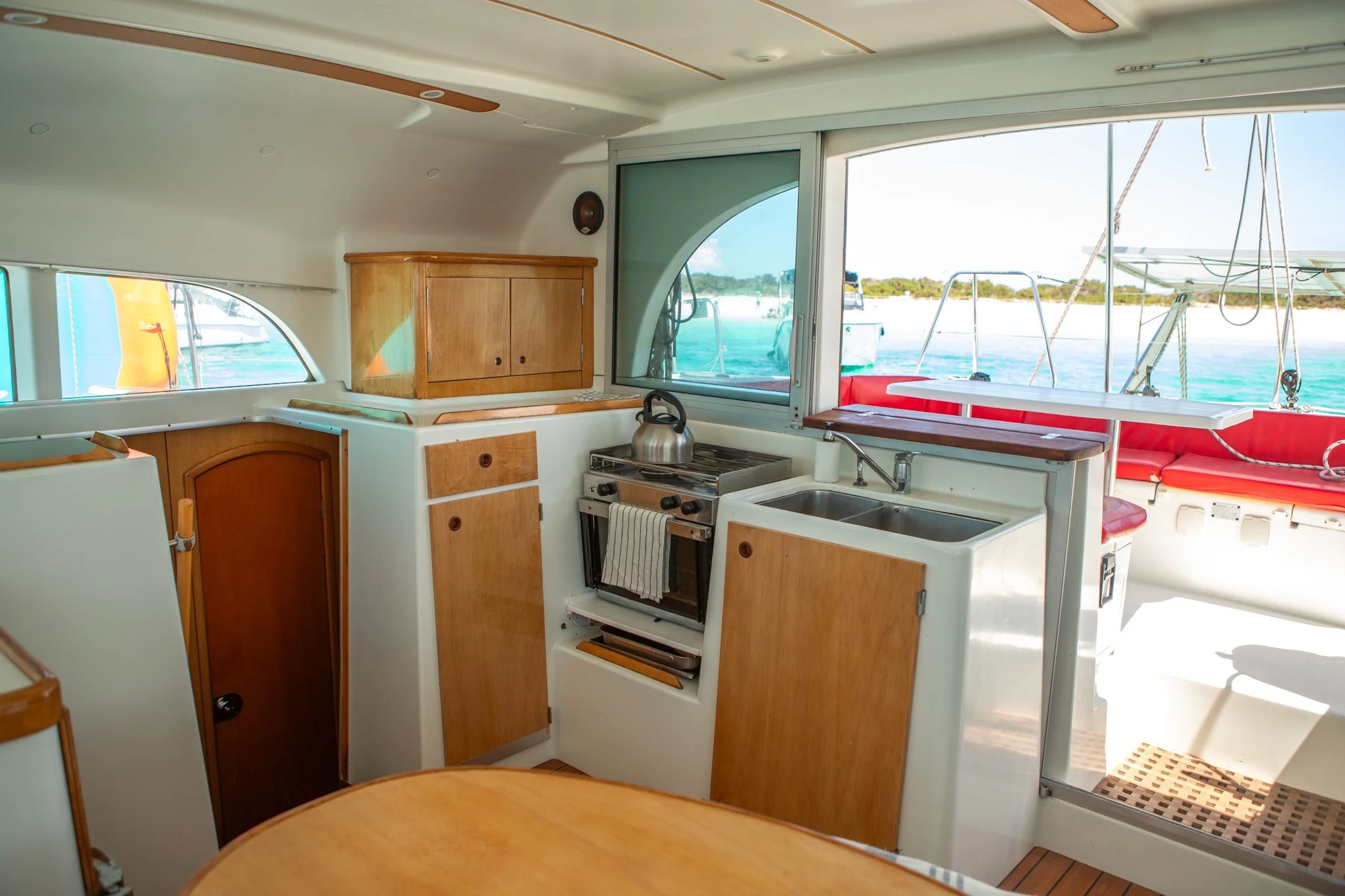 Interior de una embarcación con cocina y vistas al mar a través de ventanas.