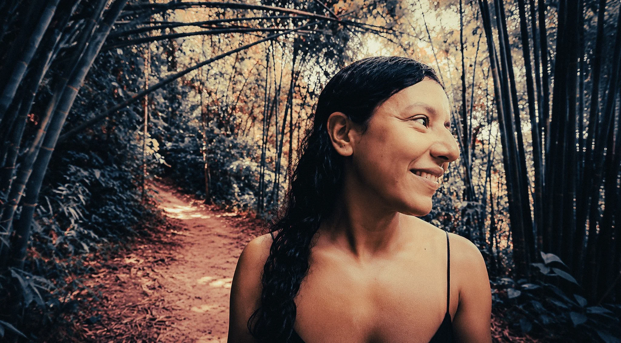 Woman walking through a bamboo forest trail in Khao Sok National Park, Thailand, surrounded by dense green jungle.