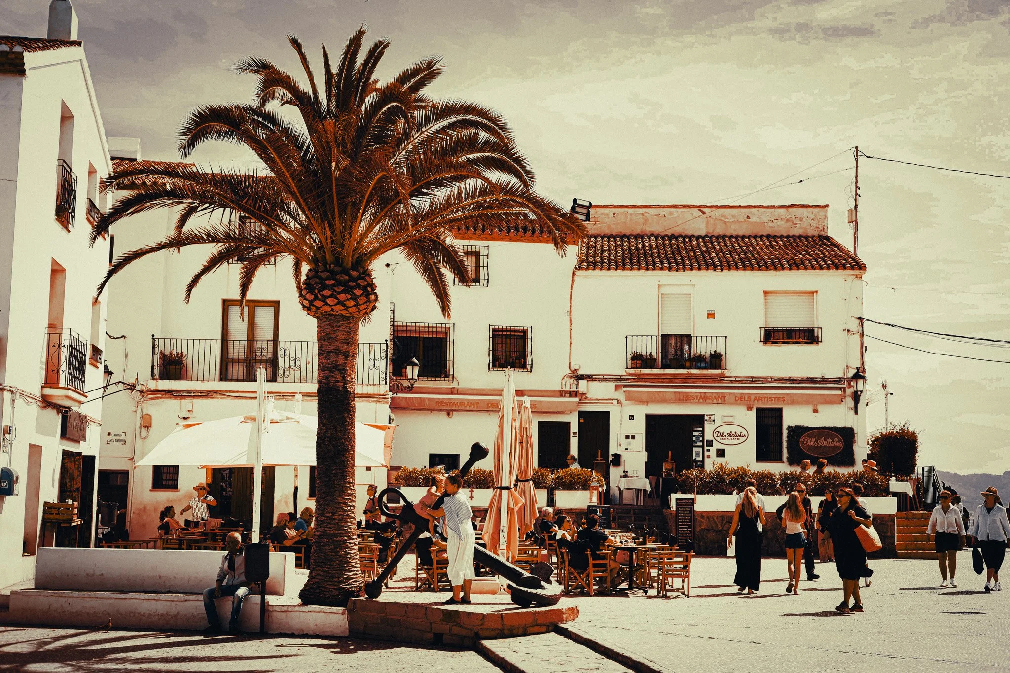 Whitewashed buildings, palm tree and outdoor cafés in Altafulla near Tarragona, a quiet coastal add-on to a Barcelona day trip.