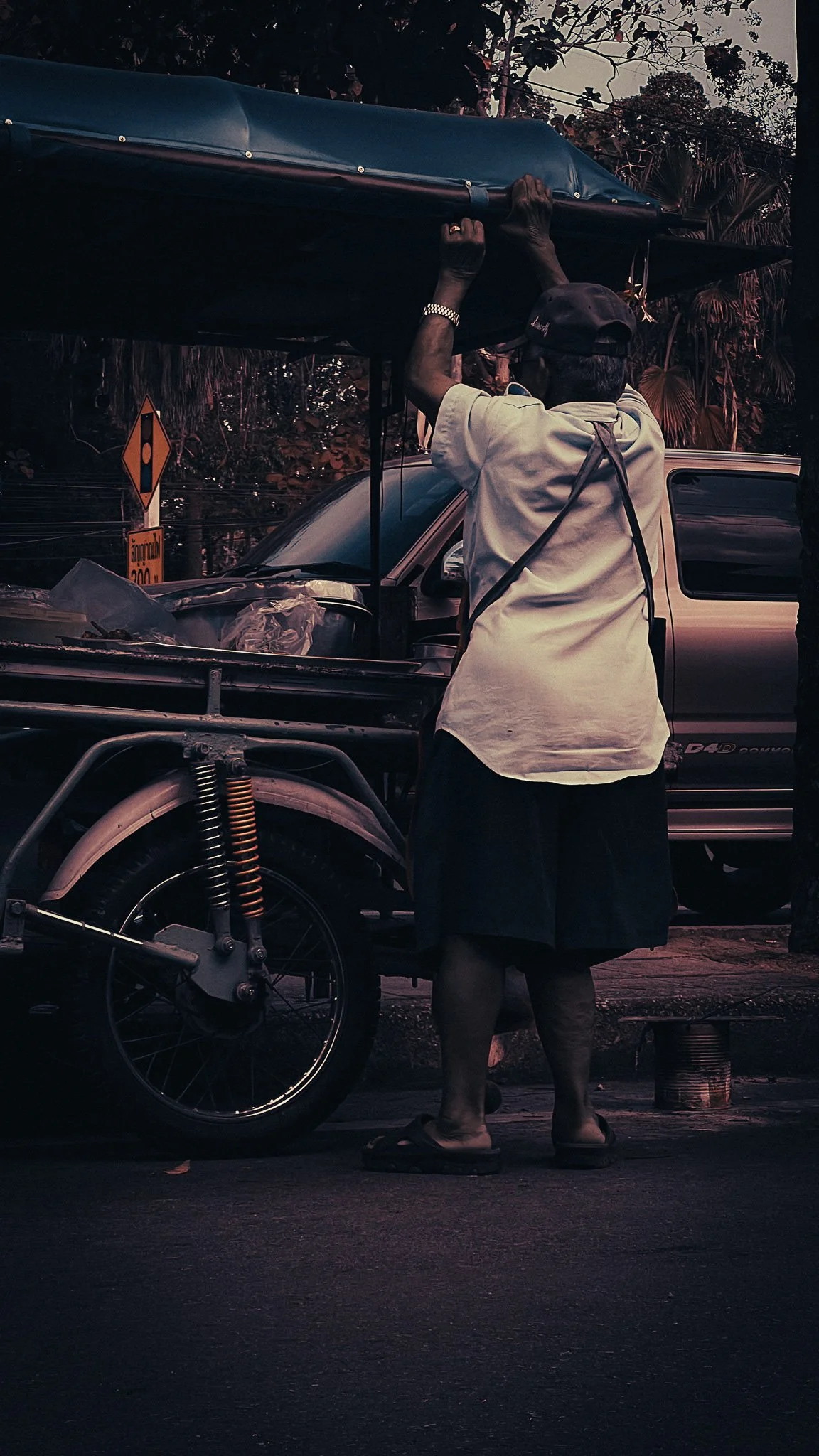 Local man adjusting a vehicle canopy near Khao Sok Village in southern Thailand.