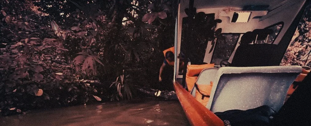 Passenger clearing a fallen tree with a machete during the boat journey through Costa Rica’s Caribbean canals from Parismina toward Moín on the route to Puerto Viejo.