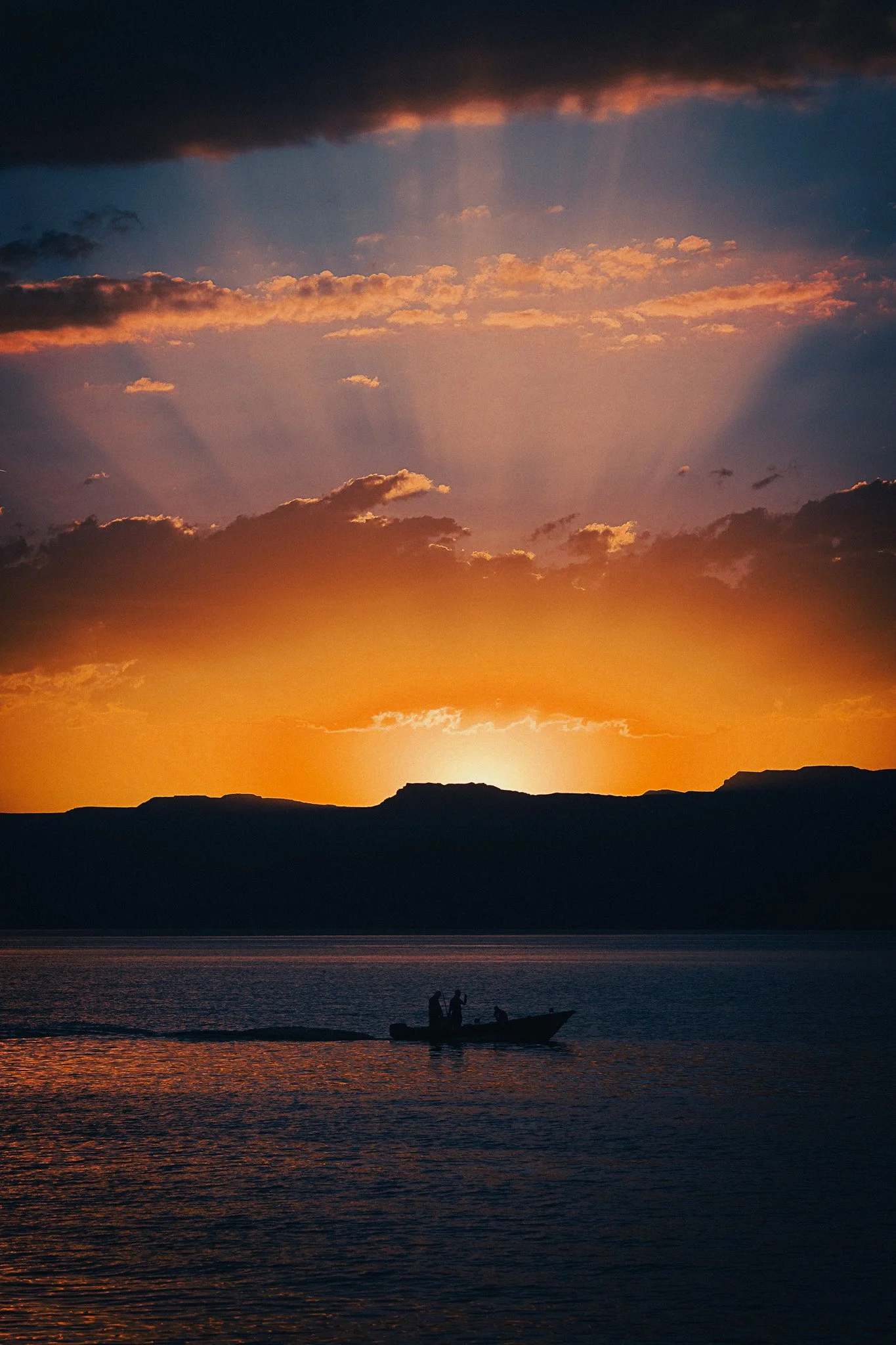 Sunset over the Red Sea in Aqaba, Jordan, with a small boat on the water and mountains in the distance.
