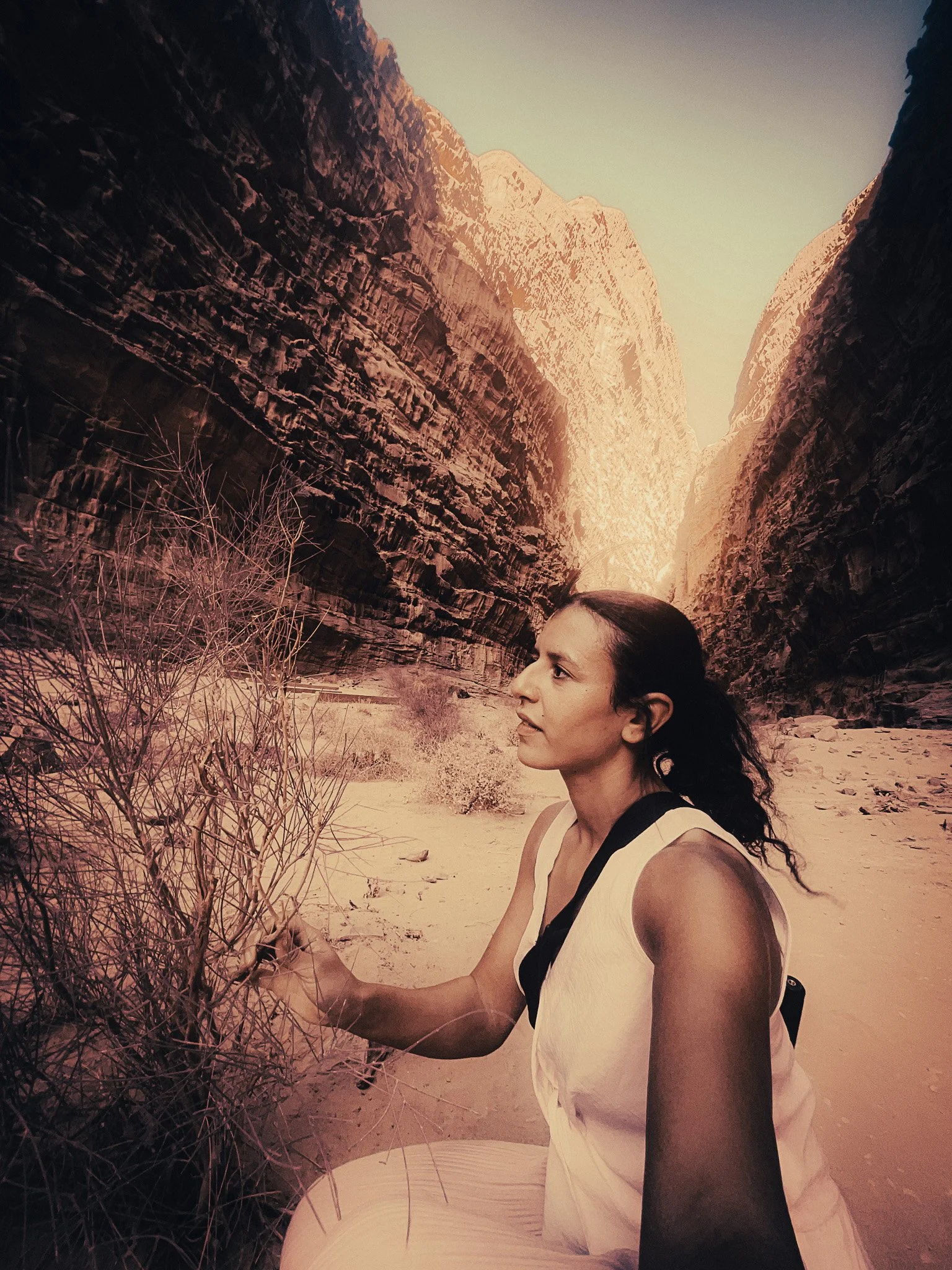 Solo female traveller standing in a dramatic Wadi Rum canyon in Jordan, surrounded by tall red sandstone cliffs.