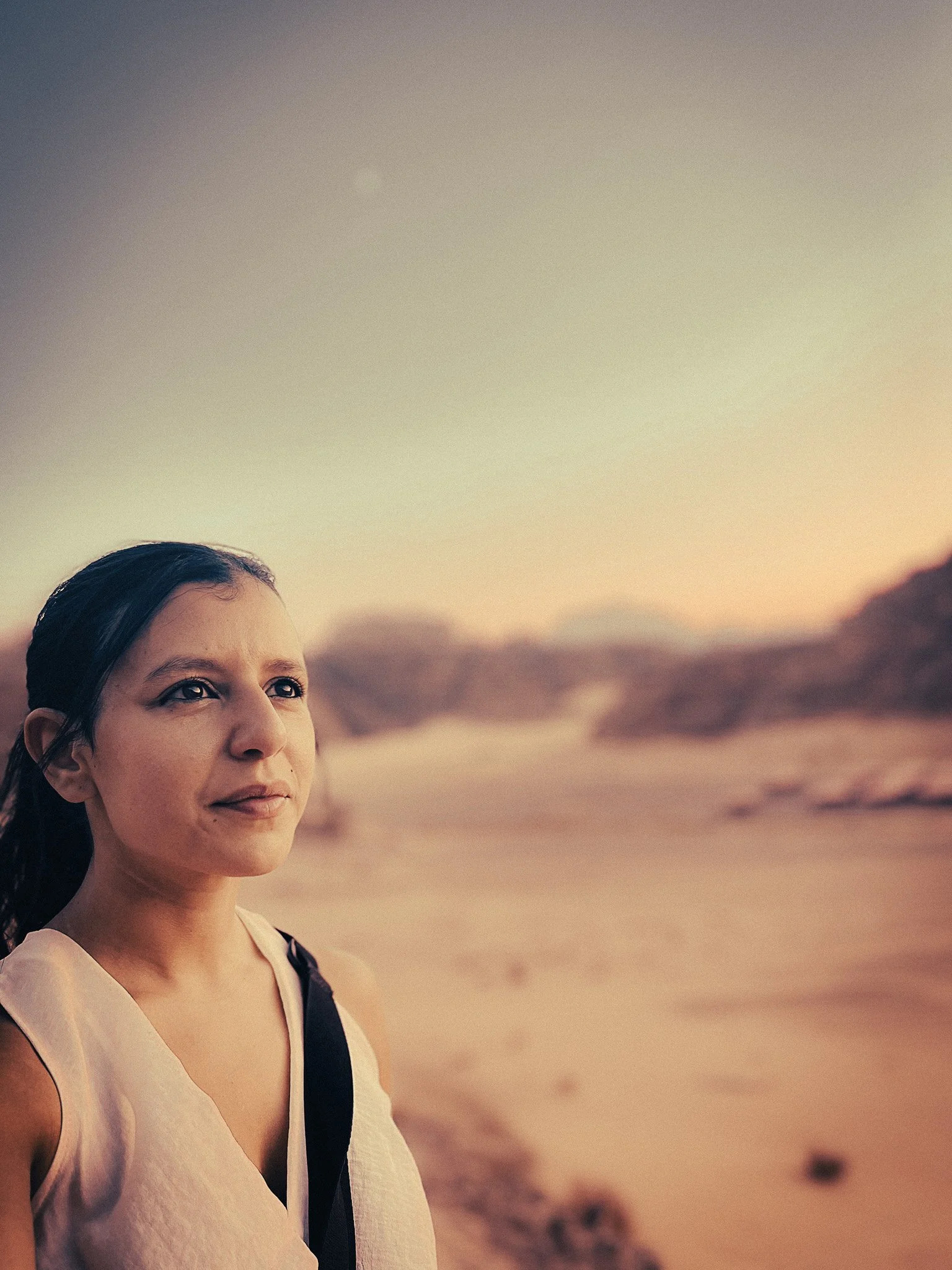 Woman standing in the Wadi Rum desert at sunset, with sandy mountains blurred in the background.