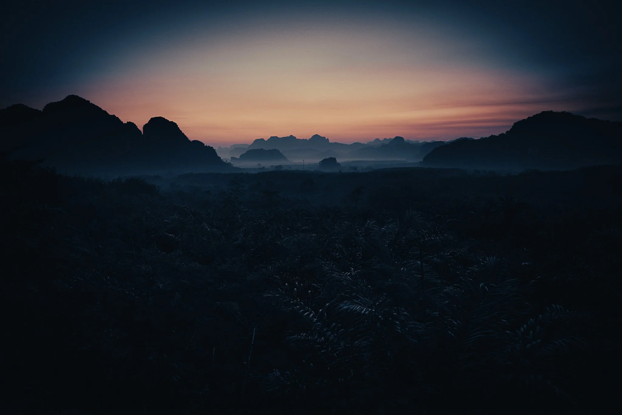 Sunrise over misty limestone mountains and rainforest in Khao Sok National Park, Thailand.