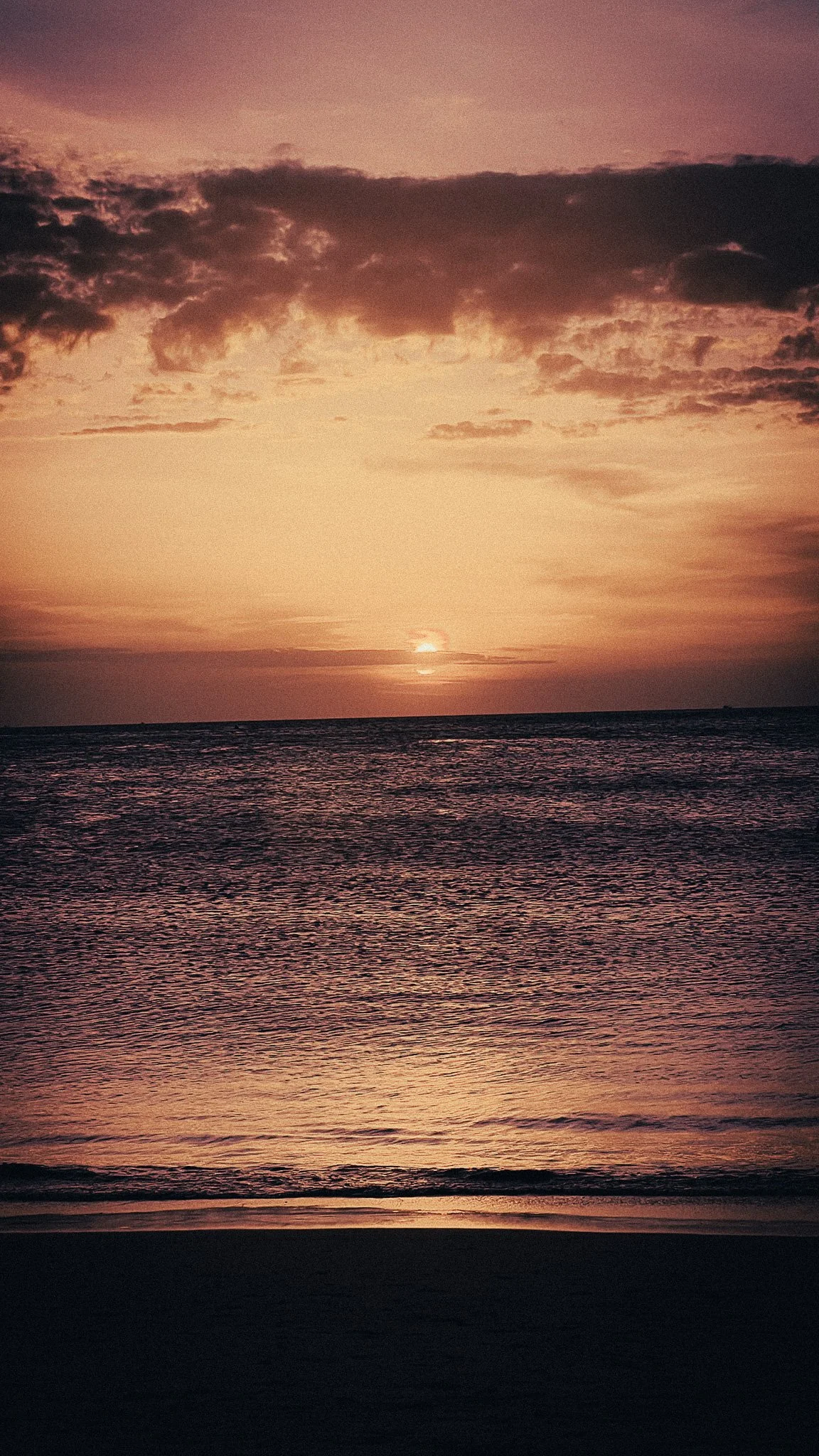 Sunset over the sea from a quiet beach in Phuket, Thailand.