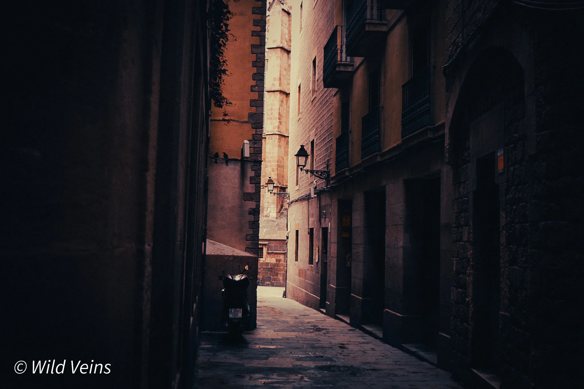 Narrow alley in Barcelona’s Gothic Quarter with old stone walls, warm light and a quiet hidden-street atmosphere.